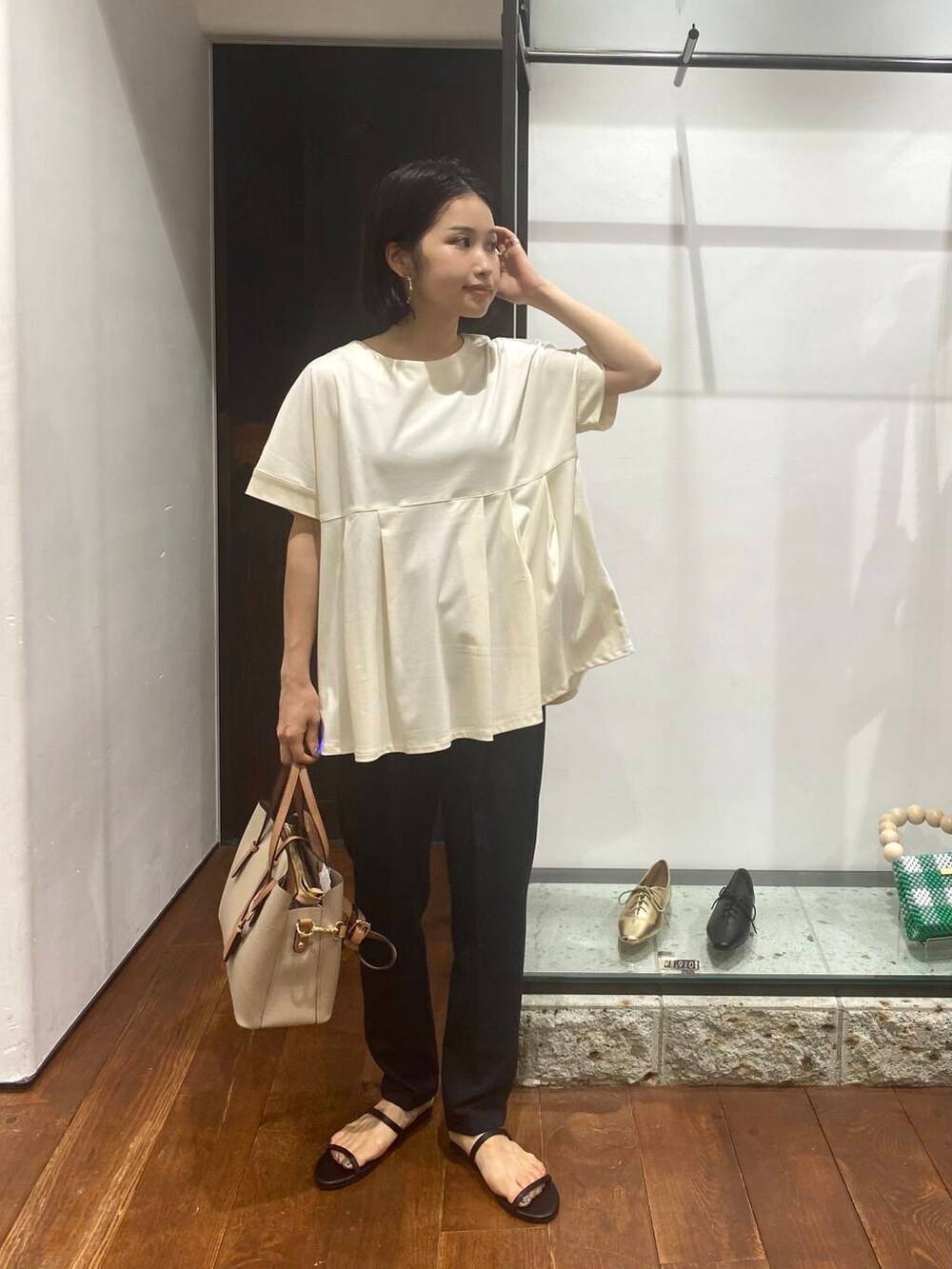 ベージュ系のトートバッグ、ブラック系のサンダル、ホワイト系のTシャツ/カットソーを着用したレディースの夏コーディネートの2枚目の写真
