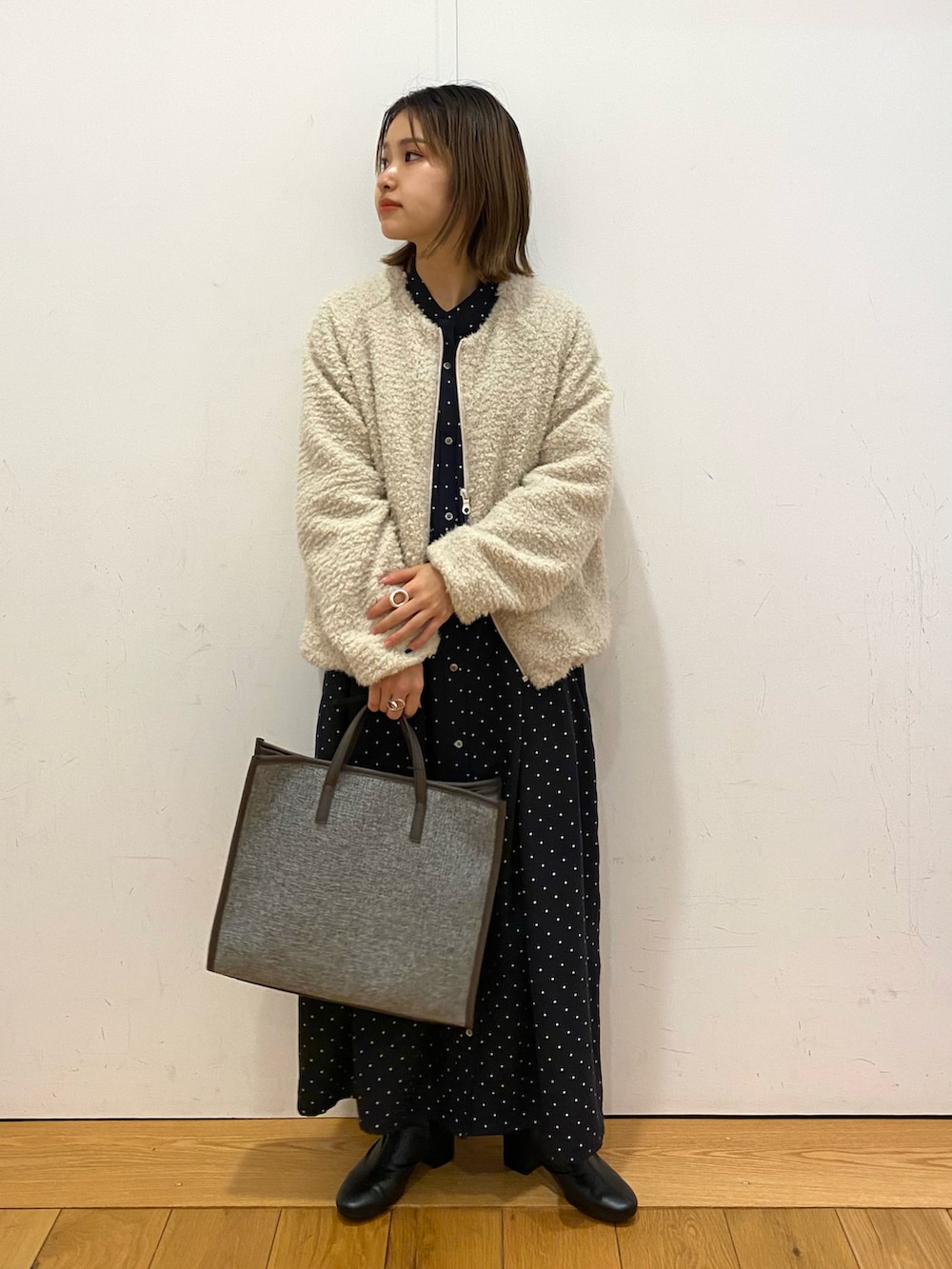 ブルー系のワンピース、ホワイト系のブルゾン、グレー系のトートバッグを着用したレディースの冬コーディネートの2枚目の写真