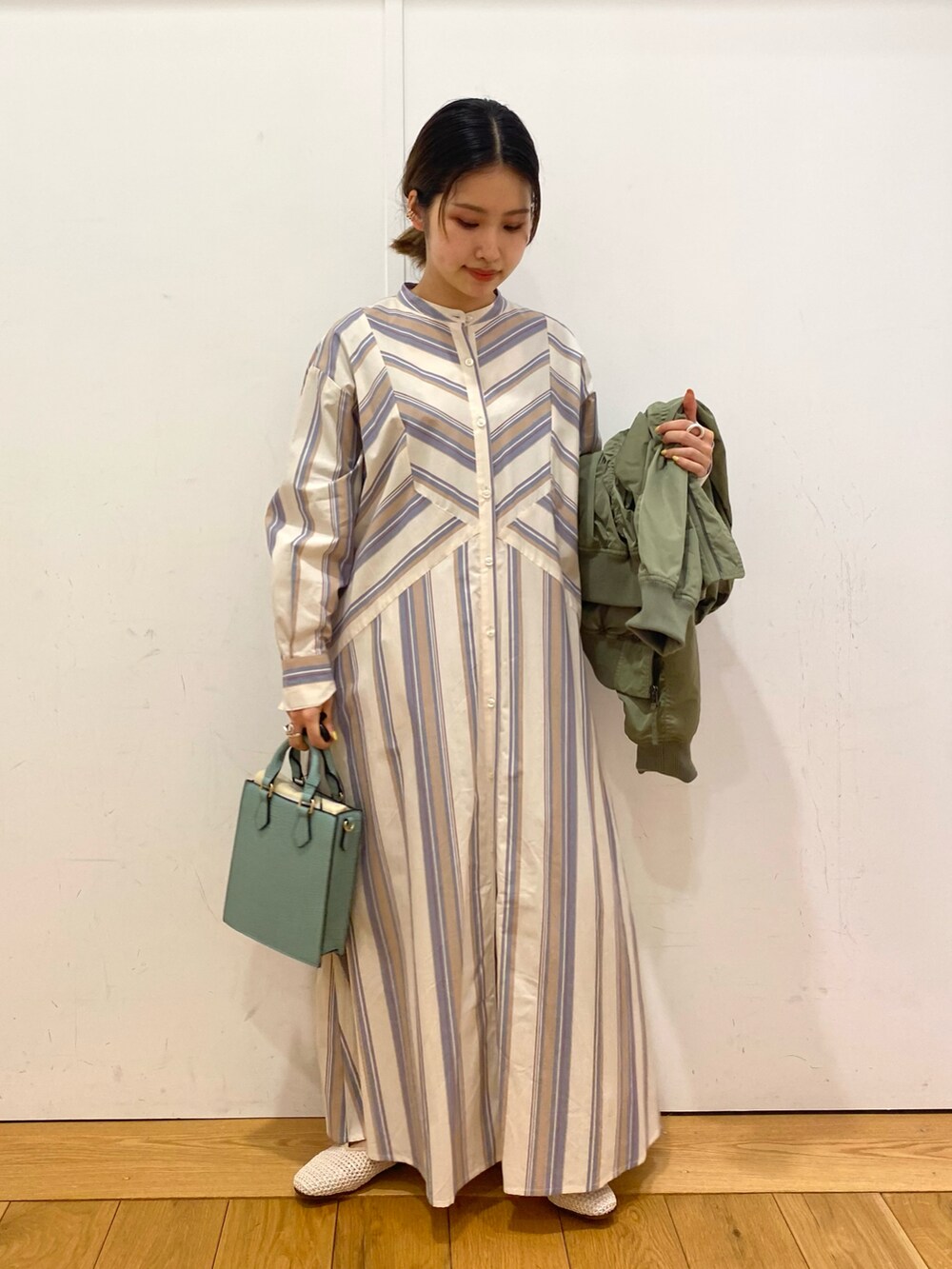 ベージュ系のワンピース、グリーン系のMA-1、グリーン系のトートバッグを着用したレディースの春コーディネートの3枚目の写真