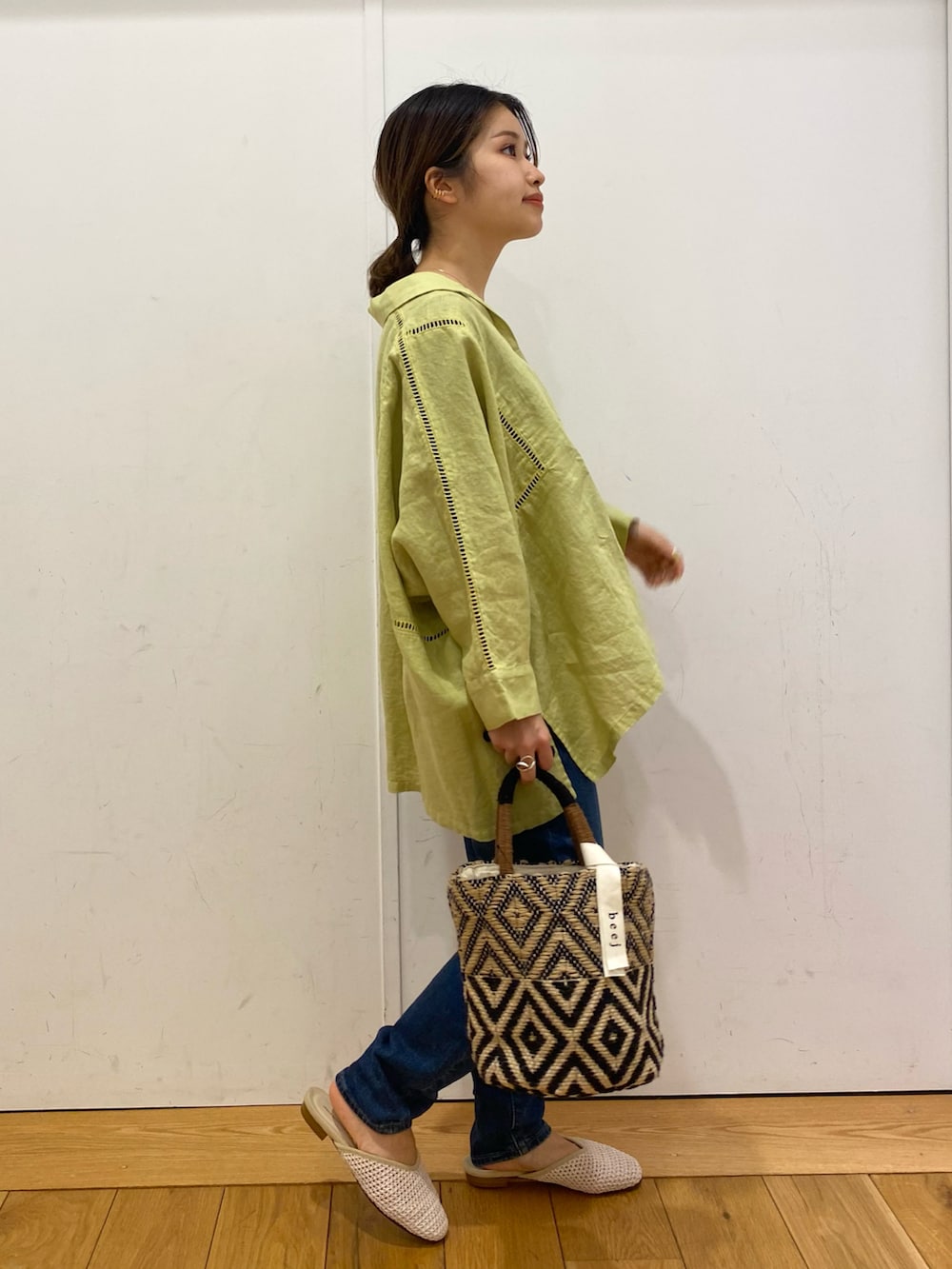 ブルー系のデニムパンツ、イエロー系のシャツ/ブラウス、ブラック系のトートバッグを着用したレディースの春コーディネートの2枚目の写真