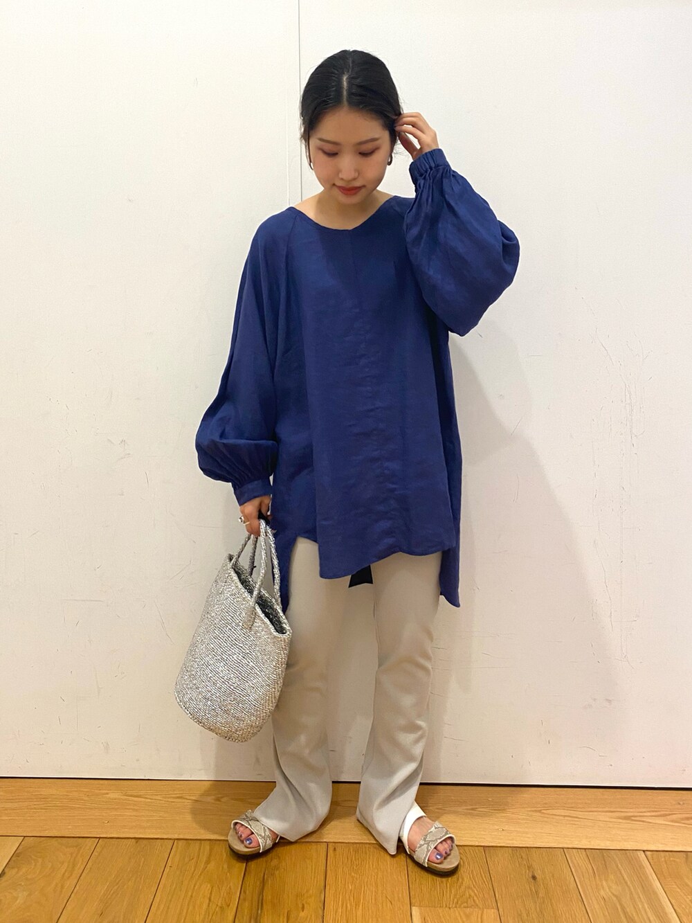 シルバー系のトートバッグ、ホワイト系のサンダル、ブルー系のシャツ/ブラウスを着用したレディースの夏コーディネートの2枚目の写真