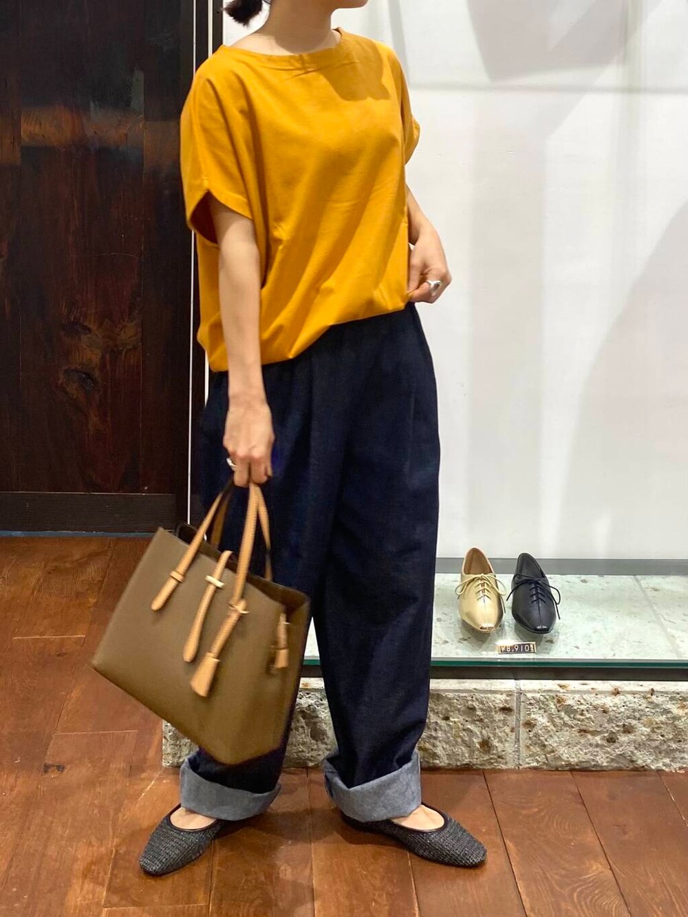 イエロー系のTシャツ/カットソー、ブラック系のパンプス、ブルー系のデニムパンツを着用したレディースの夏コーディネートの3枚目の写真