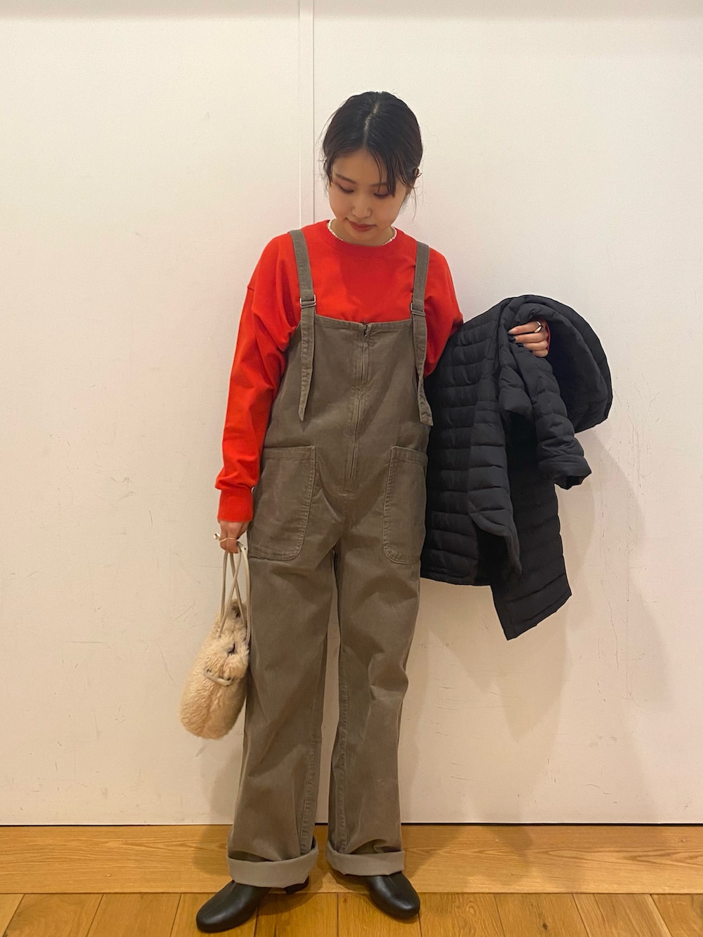 ベージュ系のハンドバッグ、グレー系のサロペット/オーバーオール、オレンジ系のニット/セーターを着用したレディースの冬コーディネートの3枚目の写真