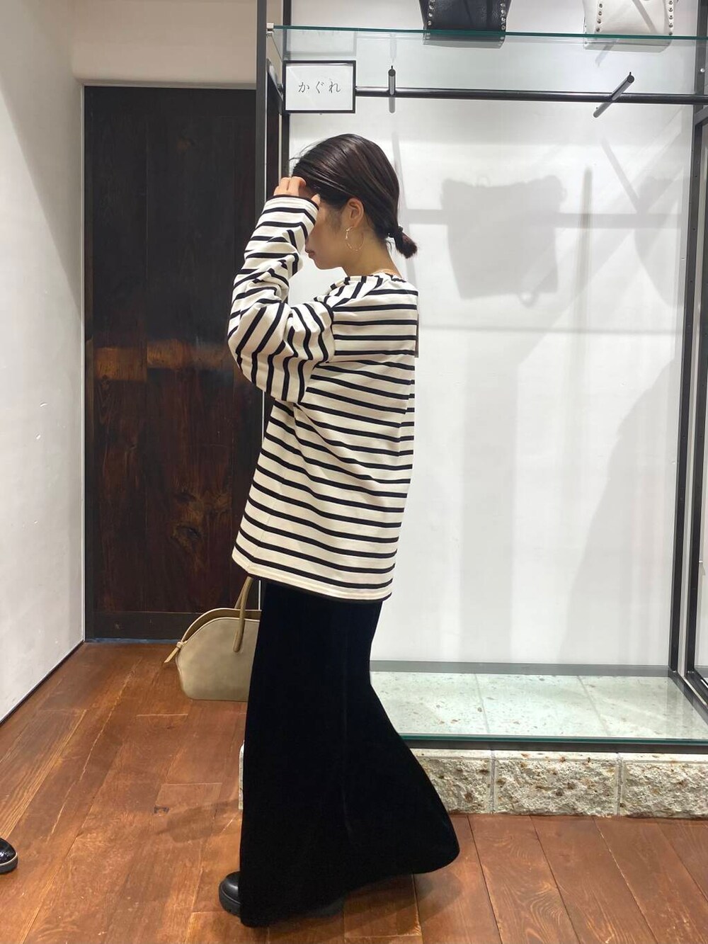 ベージュ系のハンドバッグ、ブラック系のブーツ、ブラック系のスカートを着用したレディースの秋コーディネートの3枚目の写真