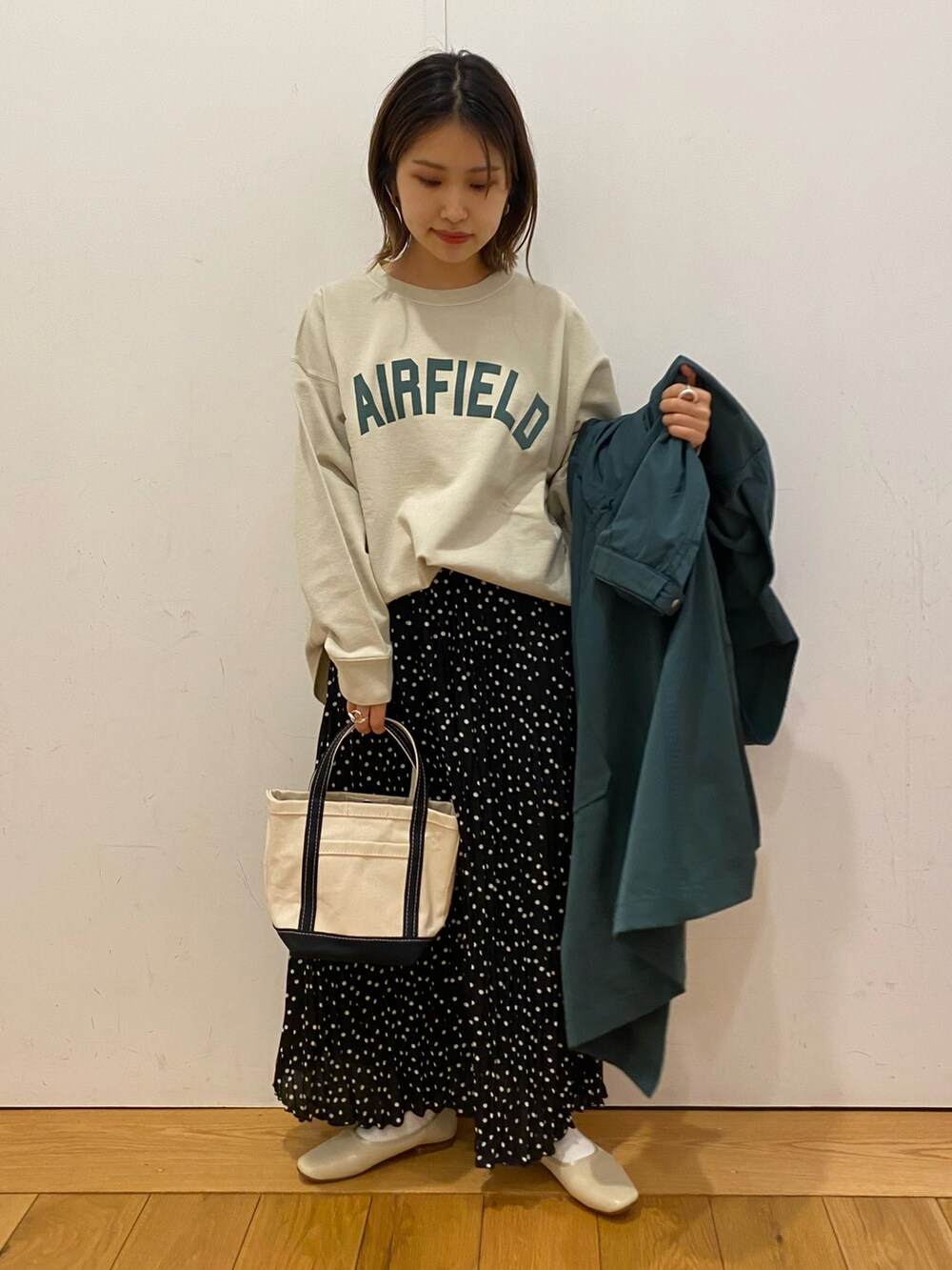 ホワイト系のパンプス、ブラック系のスカート、ブルー系のハンドバッグを着用したレディースの冬コーディネートの3枚目の写真