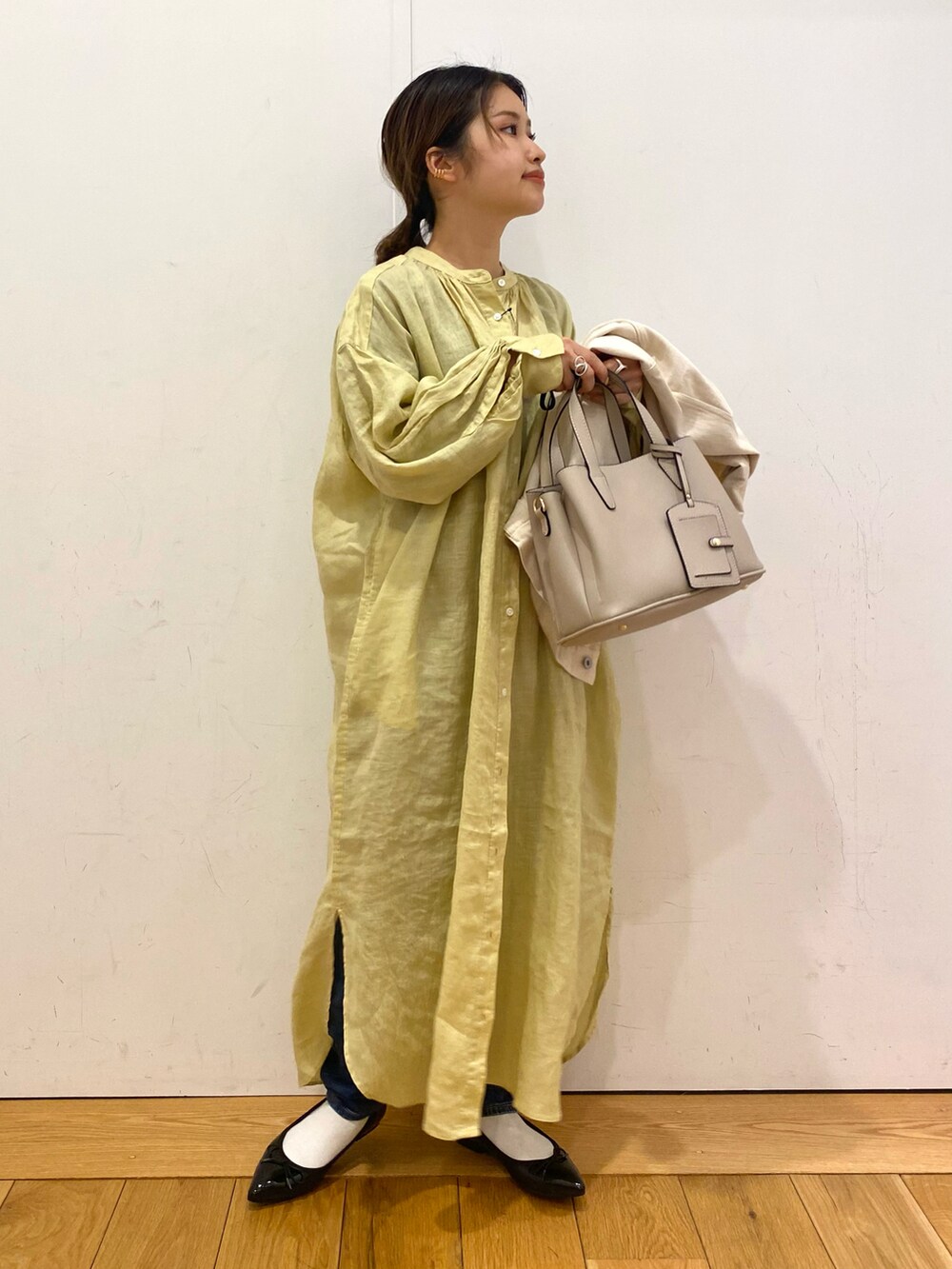 ベージュ系のトートバッグ、イエロー系のワンピース、ベージュ系のカバーオールを着用したレディースの春コーディネートの3枚目の写真