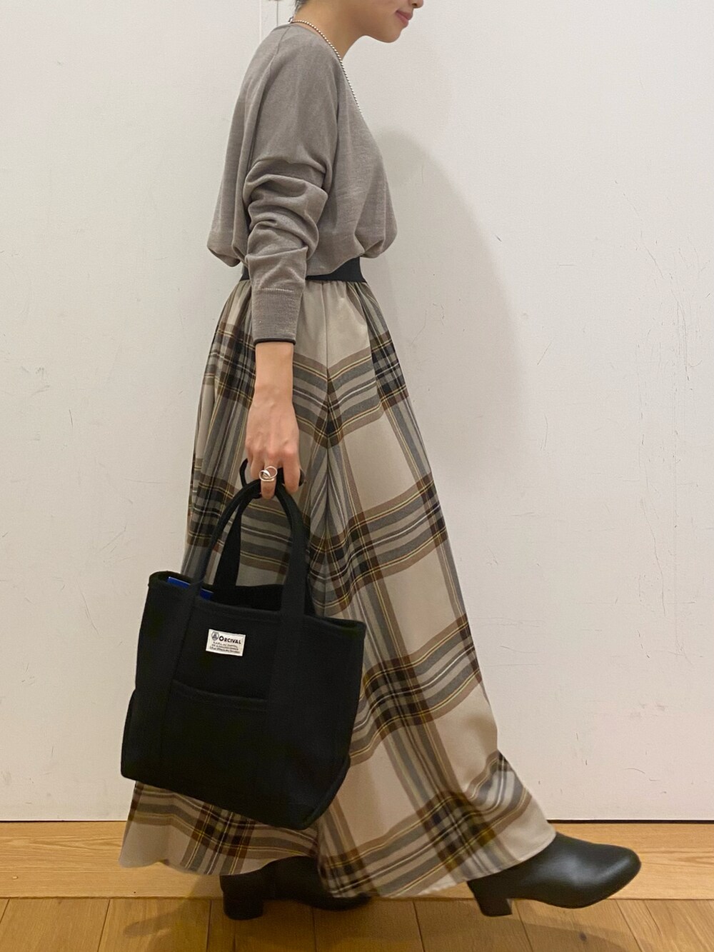 グレー系のニット/セーター、ベージュ系のスカート、ブラック系のトートバッグを着用したレディースの冬コーディネートの3枚目の写真