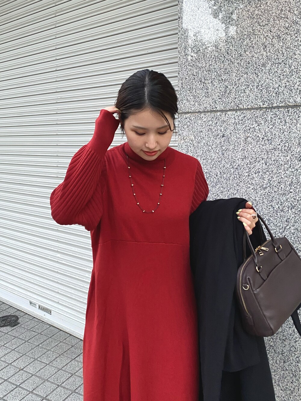 レッド系のワンピース、ブラック系のステンカラーコートを着用したレディースの秋コーディネートの3枚目の写真