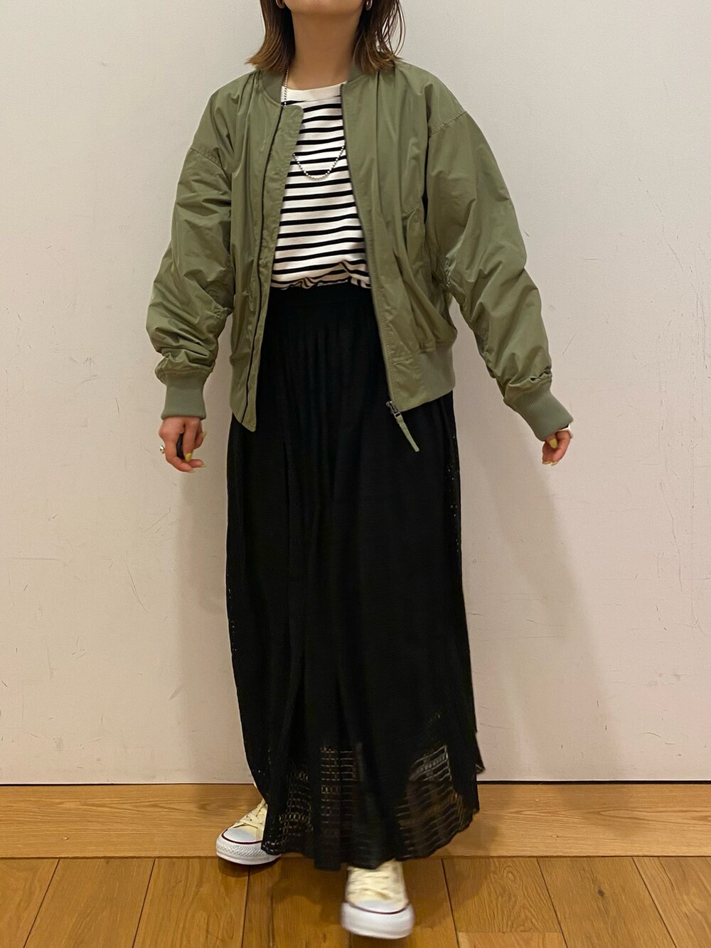 ブラック系のスカート、ホワイト系のスニーカー、ホワイト系のTシャツ/カットソーを着用したレディースの春コーディネートの2枚目の写真