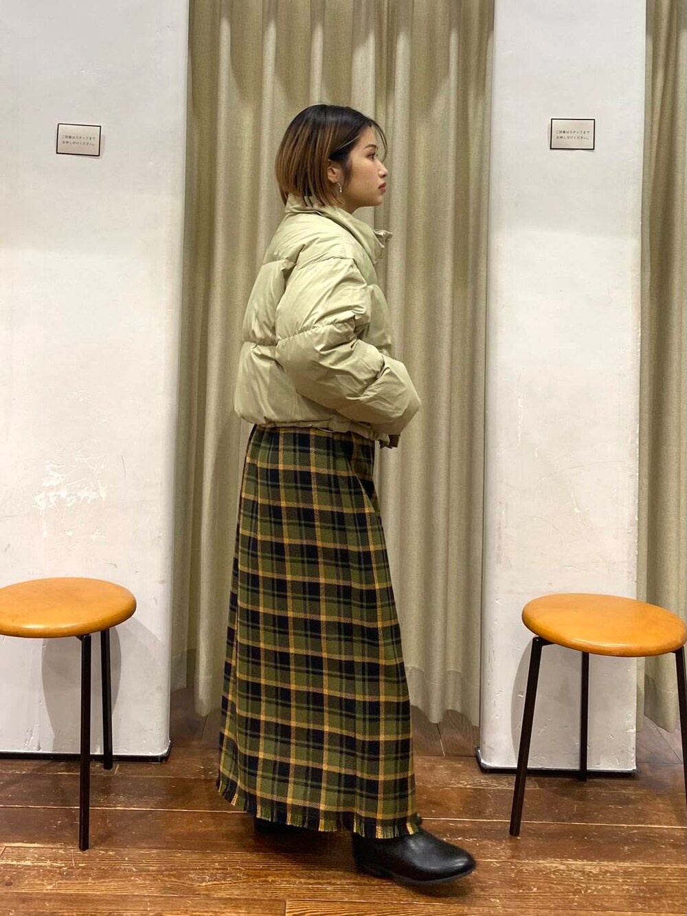 ブラック系のブーツ、グリーン系のスカート、ベージュ系のダウンジャケット/コートを着用したレディースの冬コーディネートの2枚目の写真