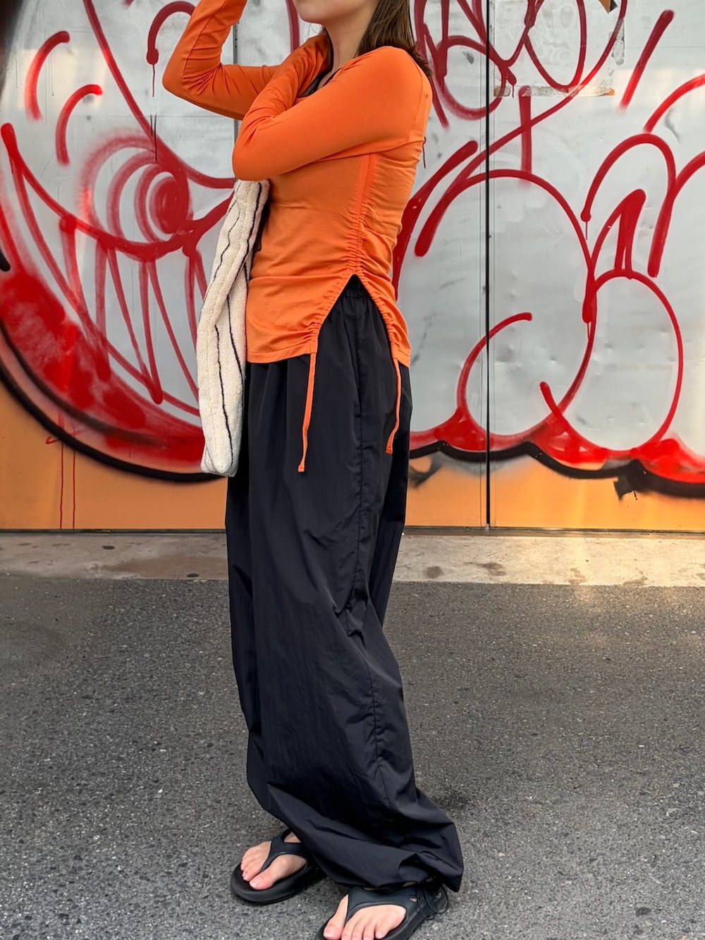 ブラック系のその他パンツ、オレンジ系のTシャツ/カットソー、ホワイト系のトートバッグを着用したレディースの夏コーディネートの5枚目の写真