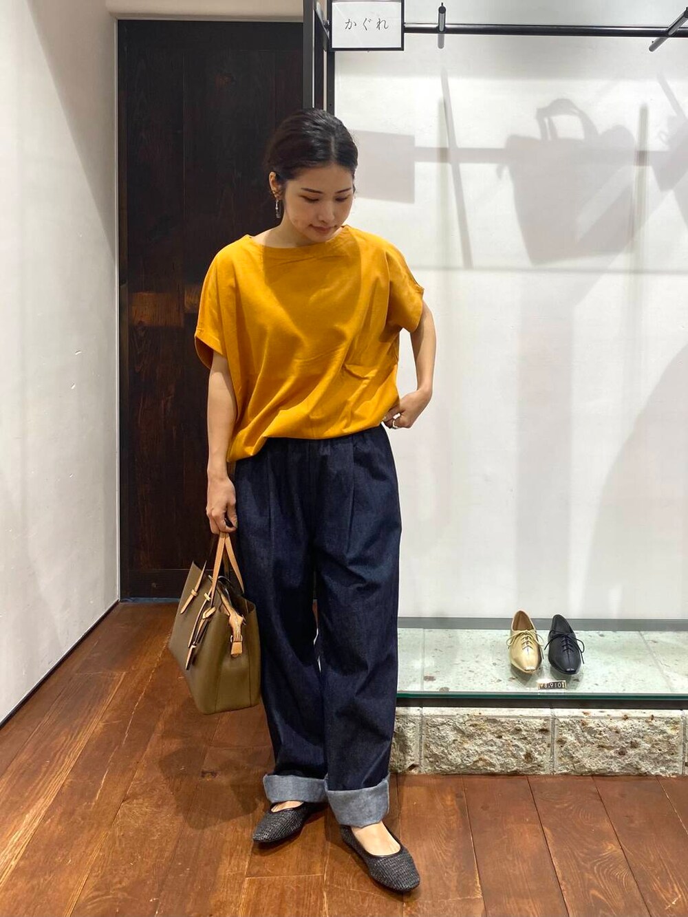 イエロー系のTシャツ/カットソー、ブラック系のパンプス、ブルー系のデニムパンツを着用したレディースの夏コーディネートの2枚目の写真