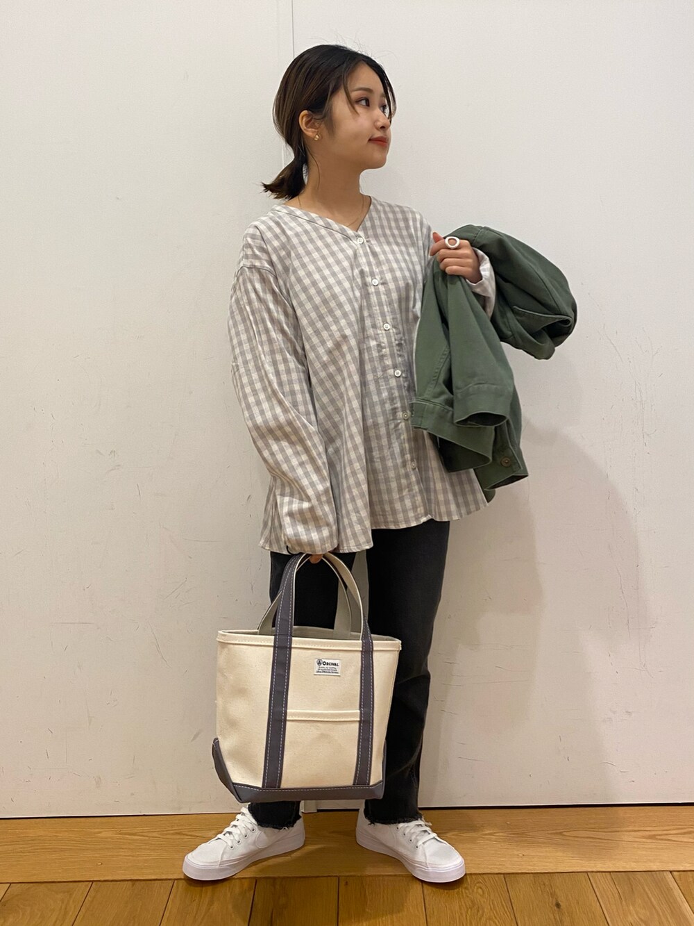 グリーン系のカバーオール、ブラック系のデニムパンツ、ホワイト系のスニーカーを着用したレディースの春コーディネートの4枚目の写真