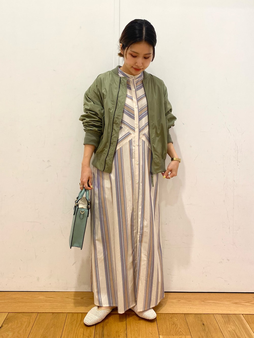 ベージュ系のワンピース、グリーン系のMA-1、グリーン系のトートバッグを着用したレディースの春コーディネートの2枚目の写真