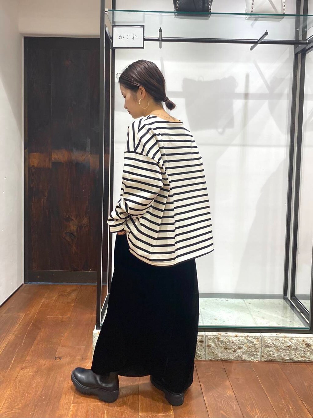 ベージュ系のハンドバッグ、ブラック系のブーツ、ブラック系のスカートを着用したレディースの秋コーディネートの4枚目の写真