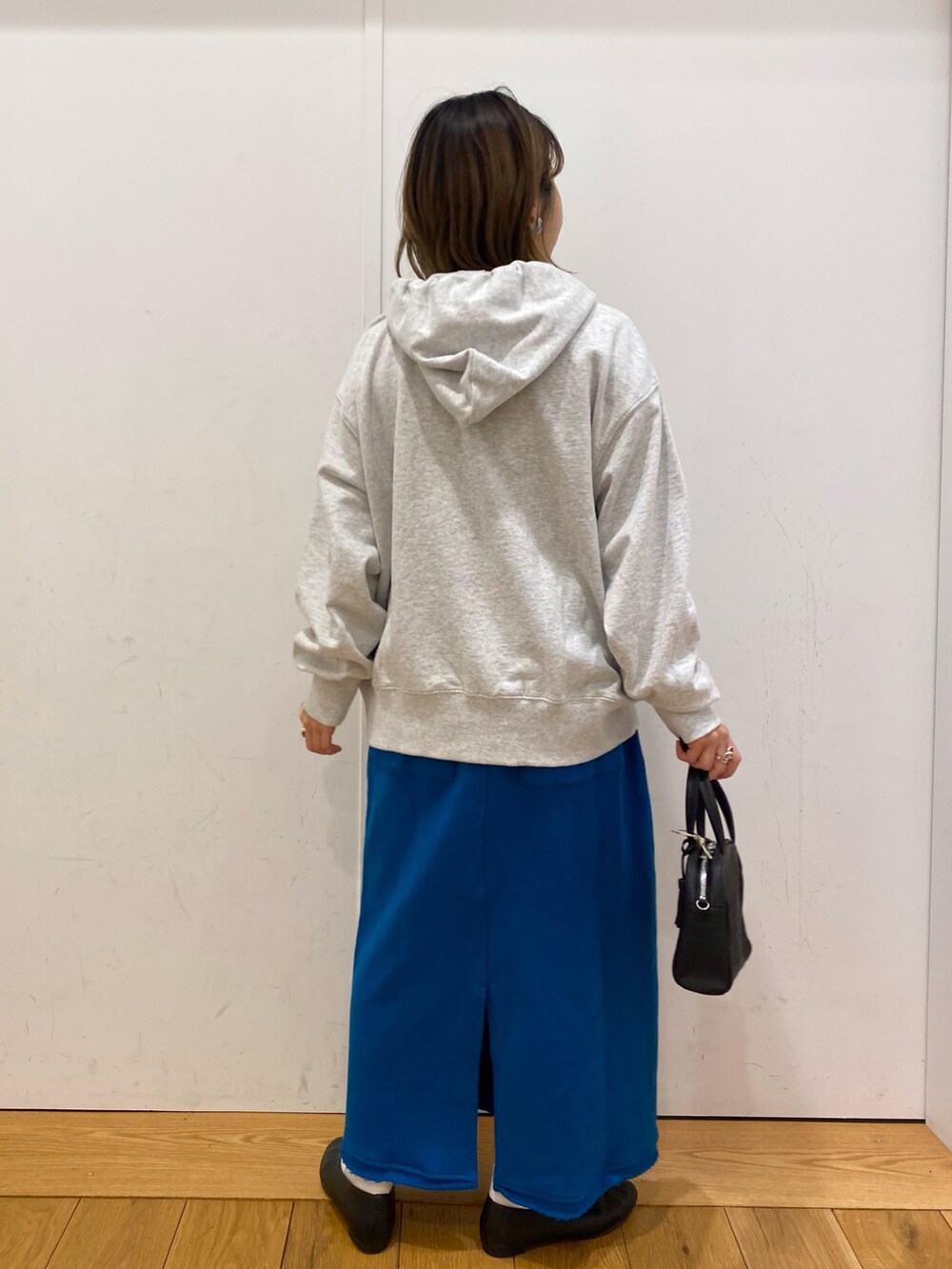 グレー系のパーカー、ブルー系のスカート、ブラック系のパンプスを着用したレディースの冬コーディネートの3枚目の写真