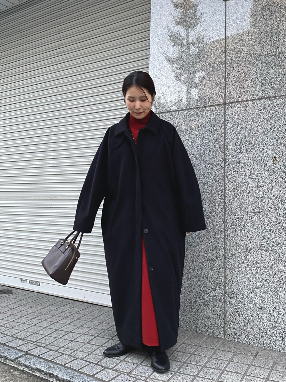 レッド系のワンピース、ブラック系のステンカラーコートを着用したレディースの秋コーディネートの2枚目の写真