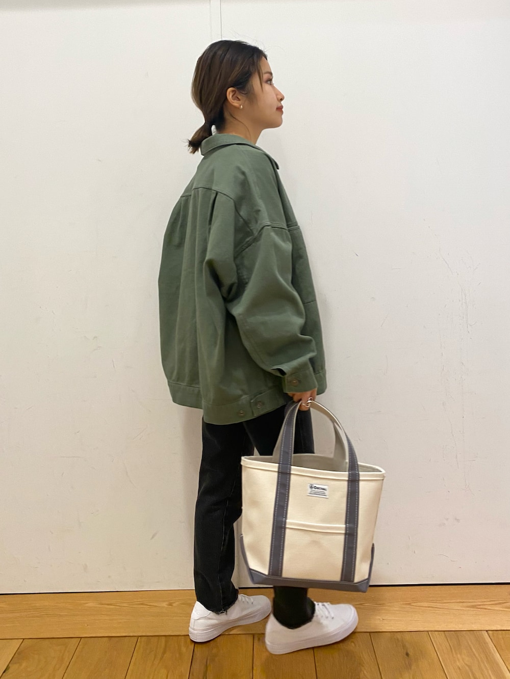 グリーン系のカバーオール、ブラック系のデニムパンツ、ホワイト系のスニーカーを着用したレディースの春コーディネートの3枚目の写真