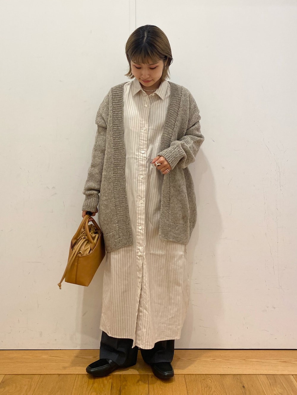 イエロー系のショルダーバッグ、ホワイト系のワンピース、グレー系のカーディガン/ボレロを着用したレディースの秋コーディネートの3枚目の写真