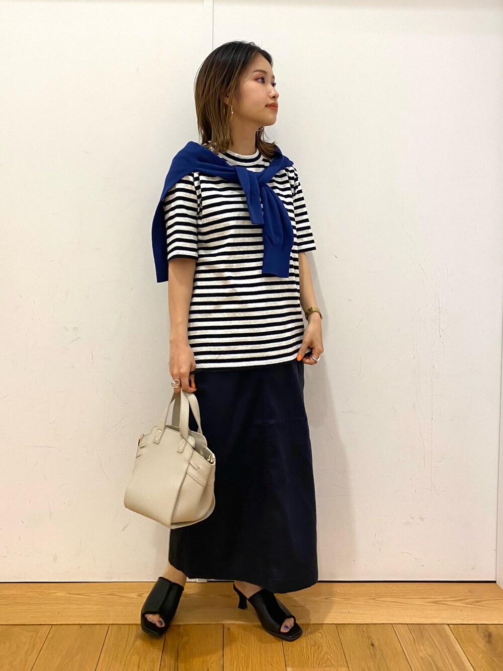 ブラウン系のハンドバッグ、ブラック系のサンダル、ブルー系のTシャツ/カットソーを着用したレディースの夏コーディネートの2枚目の写真