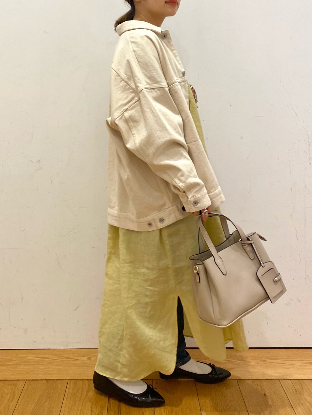 ベージュ系のトートバッグ、イエロー系のワンピース、ベージュ系のカバーオールを着用したレディースの春コーディネートの2枚目の写真