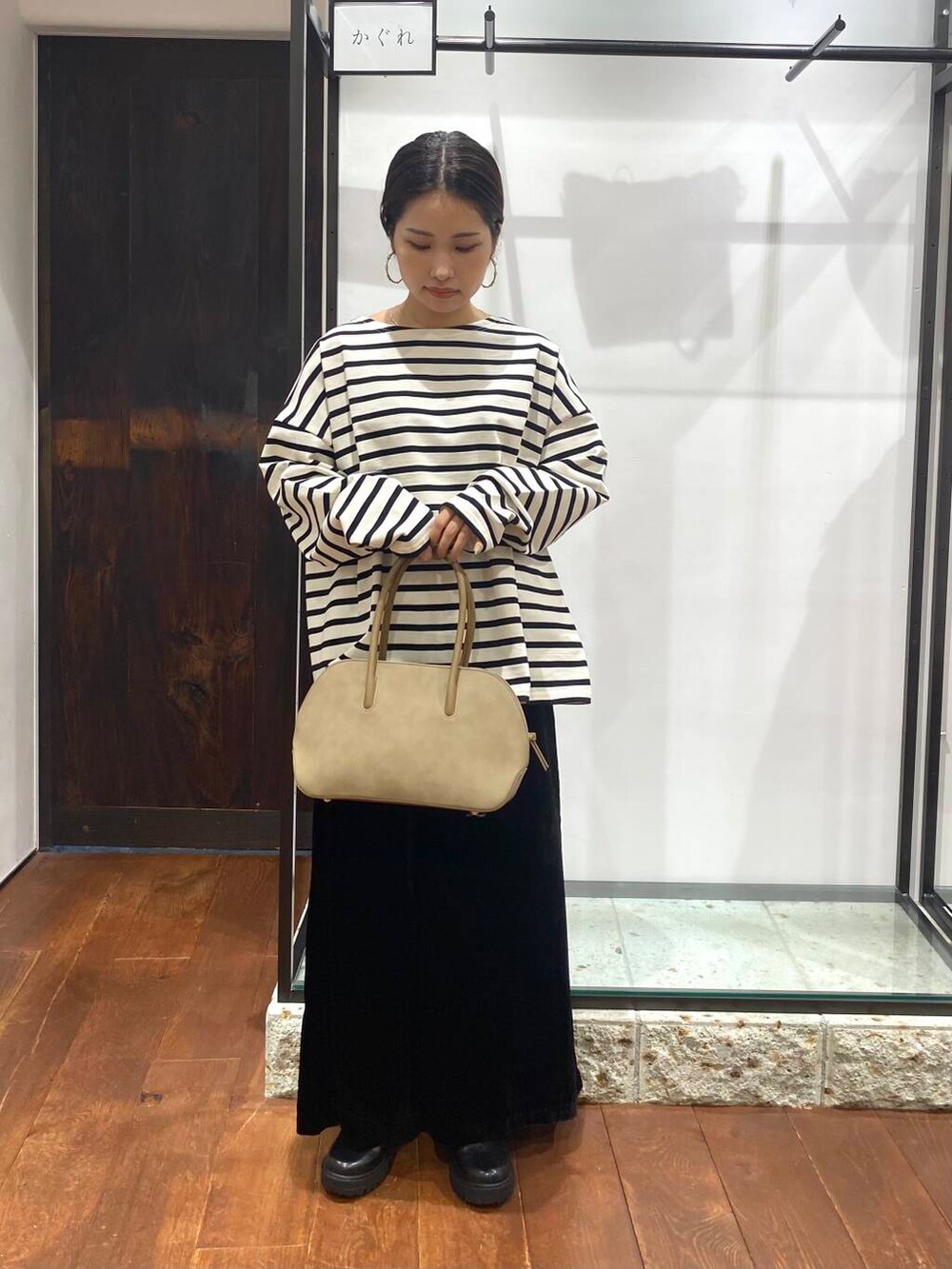 ベージュ系のハンドバッグ、ブラック系のブーツ、ブラック系のスカートを着用したレディースの秋コーディネートの5枚目の写真