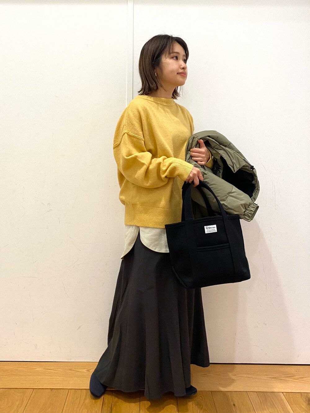 イエロー系のニット/セーター、グレー系のタンクトップ、グレー系のスカートを着用したレディースの冬コーディネートの2枚目の写真