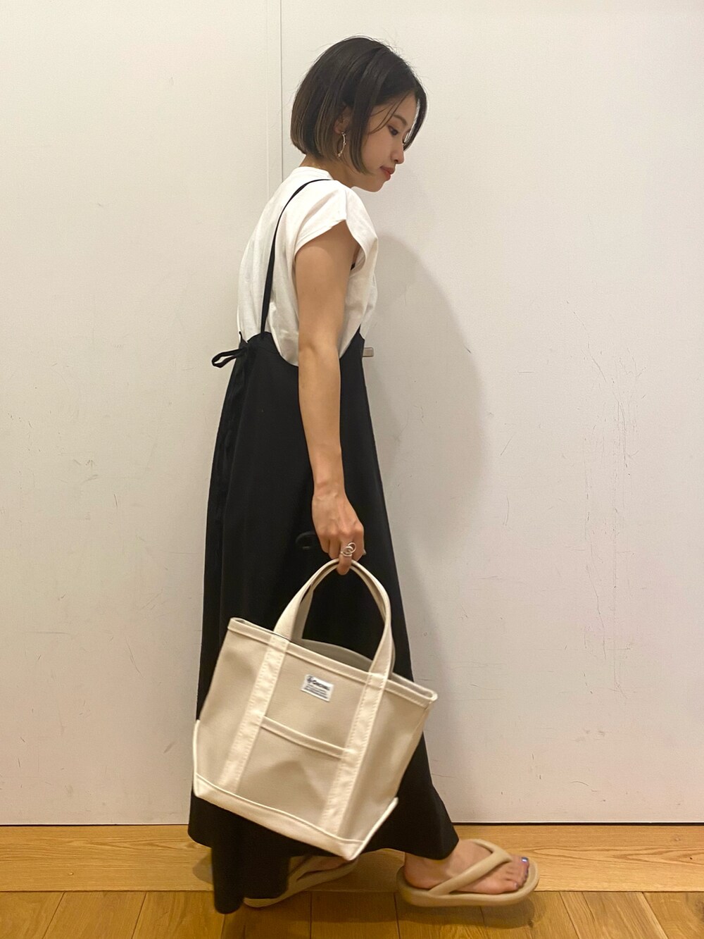 ホワイト系のトートバッグ、ベージュ系のサンダル、ブラック系のスカートを着用したレディースの秋コーディネートの2枚目の写真