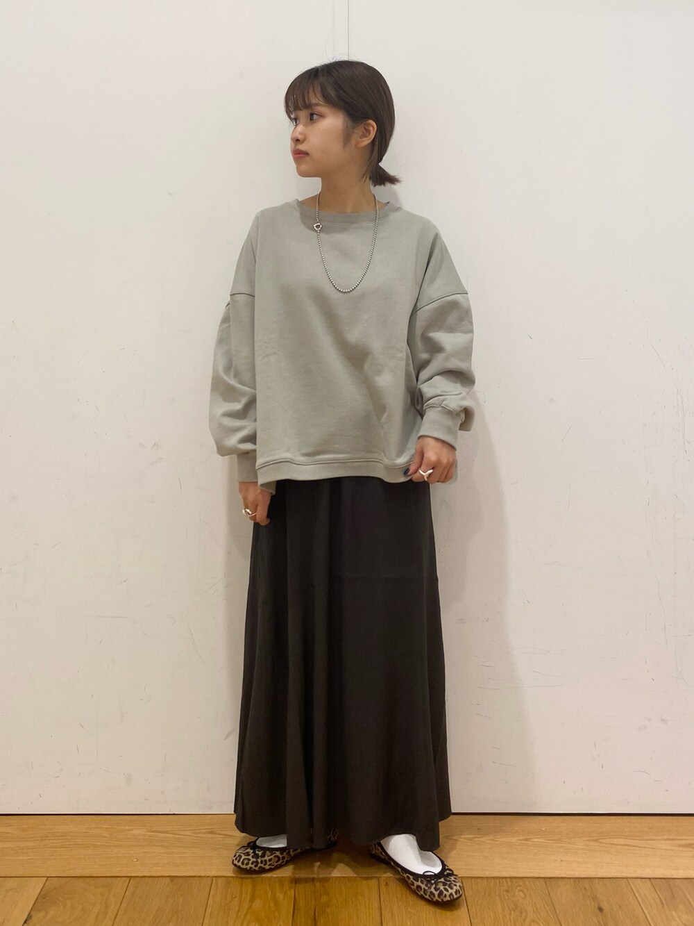 グリーン系のスウェット、グレー系のスカート、グレー系のその他アウターを着用したレディースの冬コーディネートの3枚目の写真