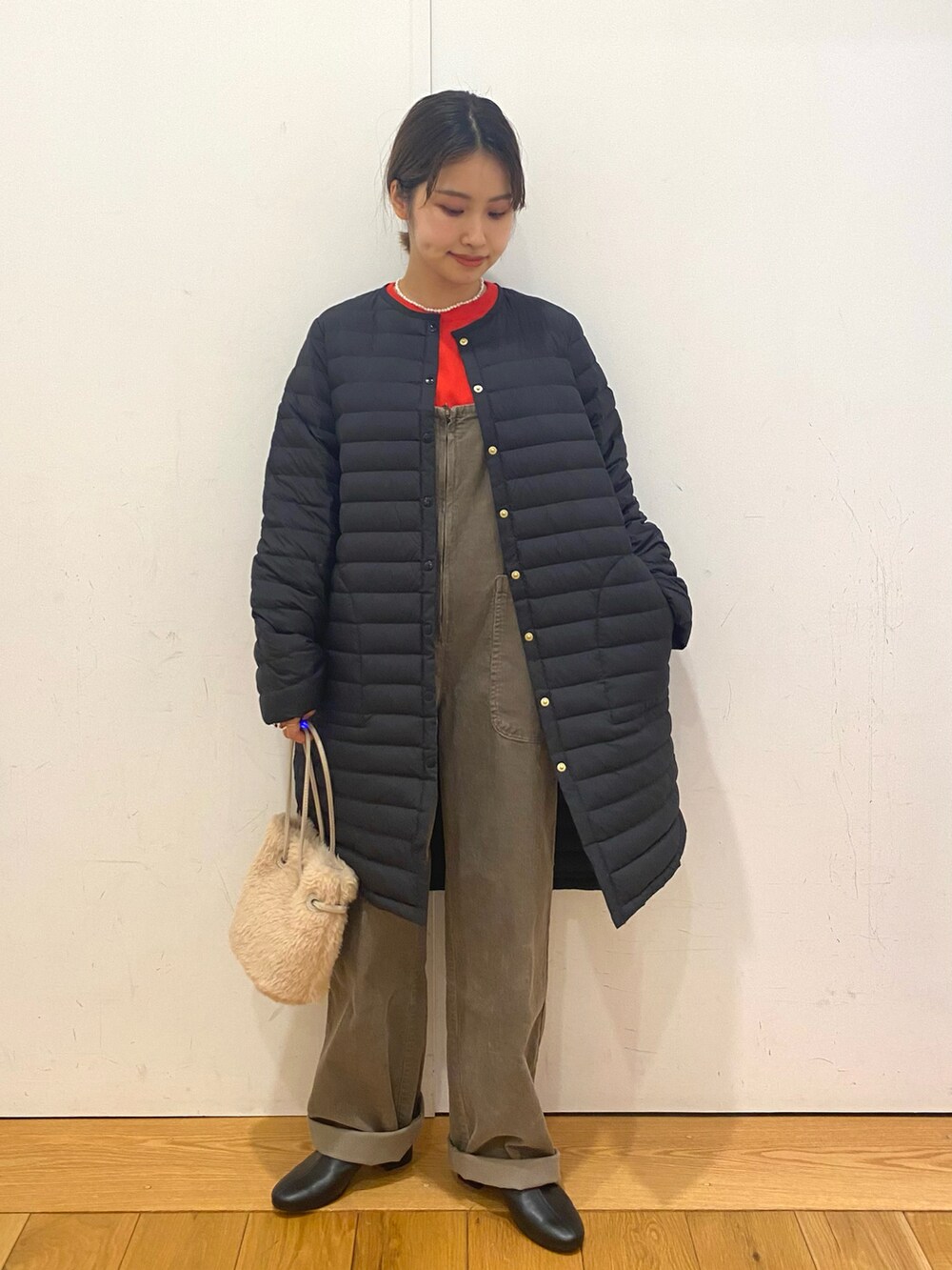 ベージュ系のハンドバッグ、グレー系のサロペット/オーバーオール、オレンジ系のニット/セーターを着用したレディースの冬コーディネートの2枚目の写真