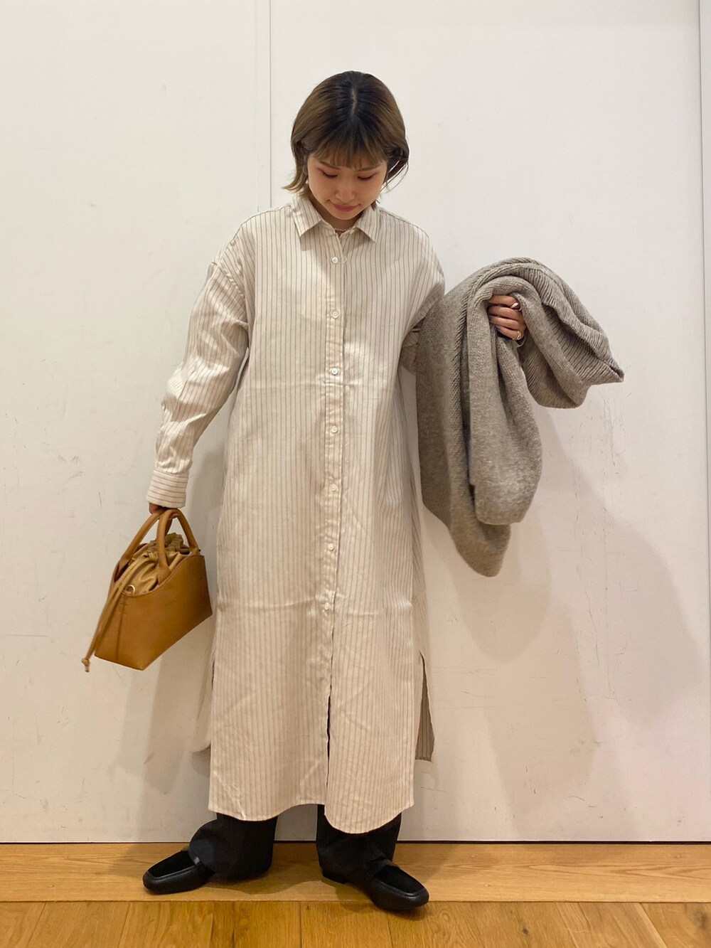 イエロー系のショルダーバッグ、ホワイト系のワンピース、グレー系のカーディガン/ボレロを着用したレディースの秋コーディネートの2枚目の写真