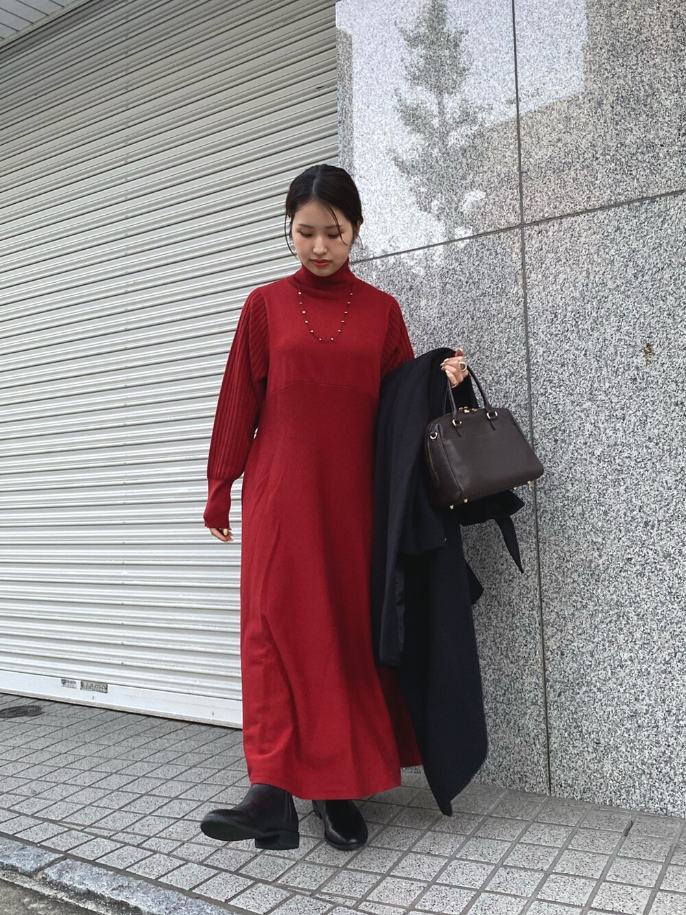 レッド系のワンピース、ブラック系のステンカラーコートを着用したレディースの秋コーディネートの4枚目の写真
