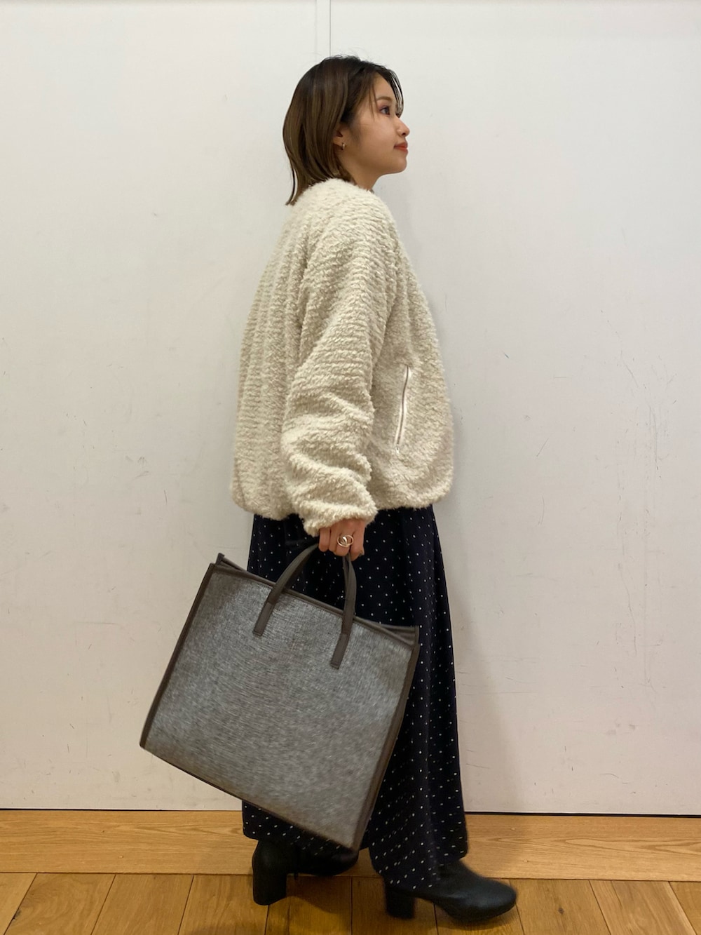 ブルー系のワンピース、ホワイト系のブルゾン、グレー系のトートバッグを着用したレディースの冬コーディネートの3枚目の写真