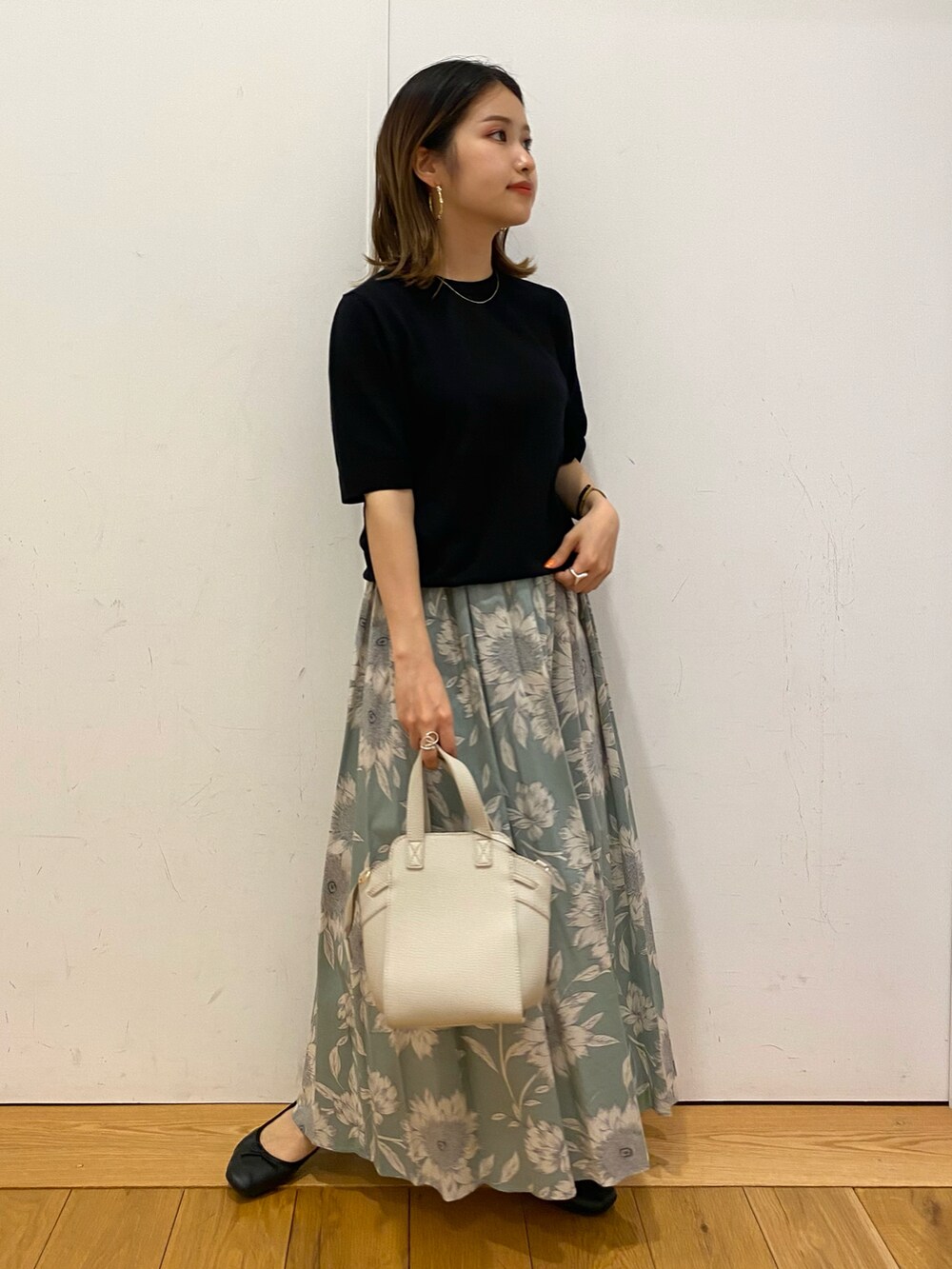 ブラック系のニット/セーター、グリーン系のスカート、ホワイト系のハンドバッグを着用したレディースの夏コーディネートの2枚目の写真