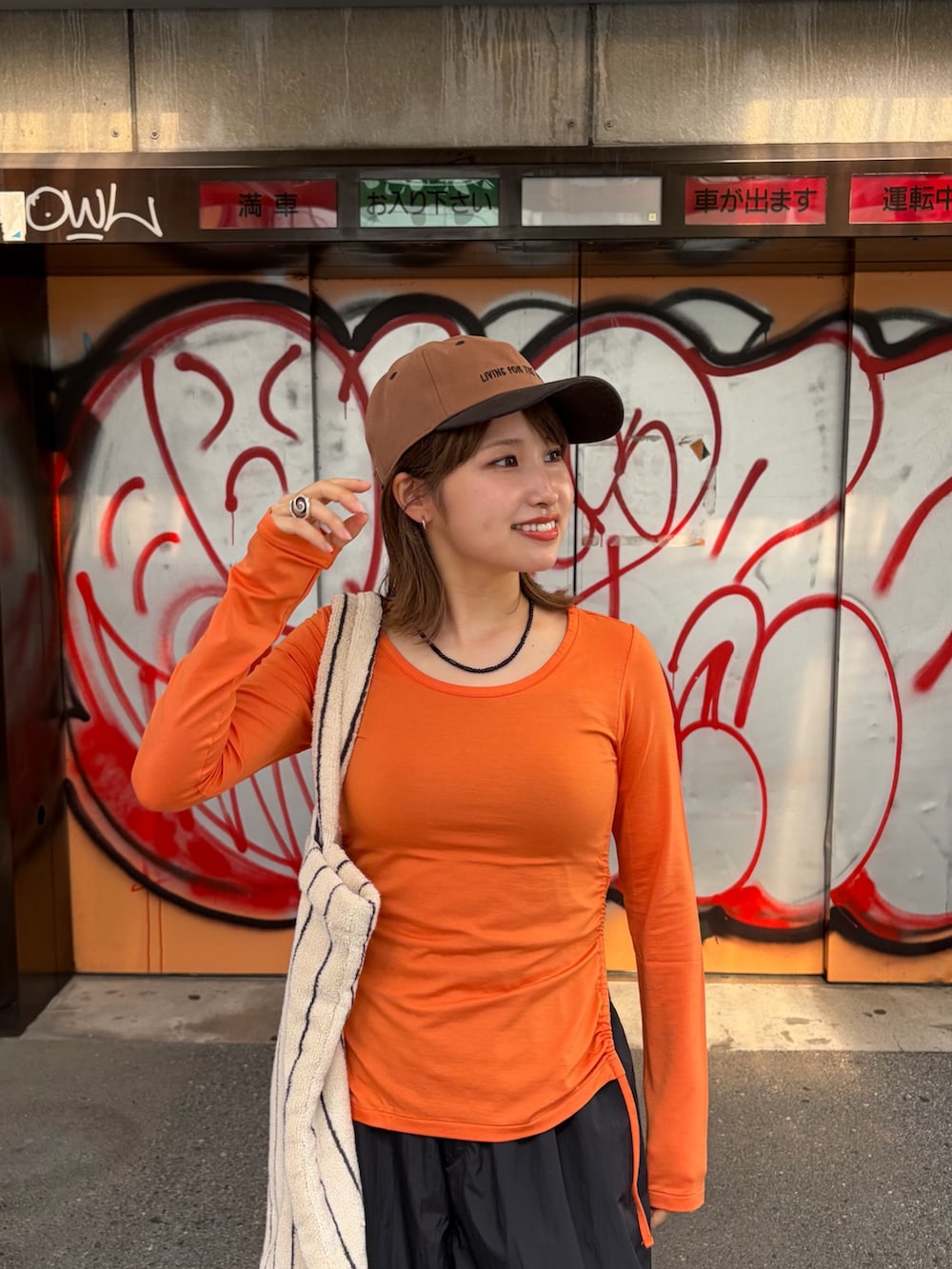 ブラック系のその他パンツ、オレンジ系のTシャツ/カットソー、ホワイト系のトートバッグを着用したレディースの夏コーディネートの4枚目の写真