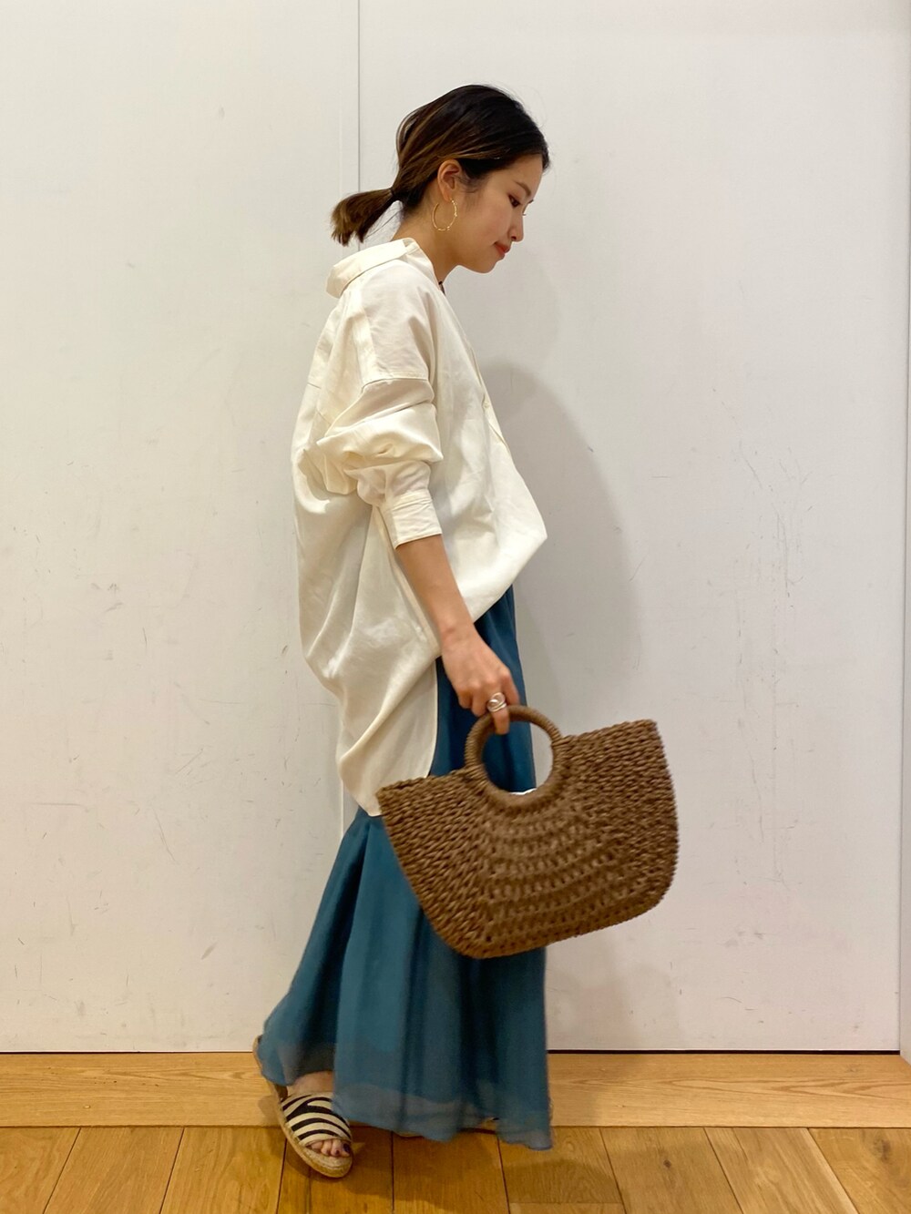 ブラウン系のハンドバッグ、ホワイト系のシャツ/ブラウス、ブルー系のスカートを着用したレディースの夏コーディネートの3枚目の写真