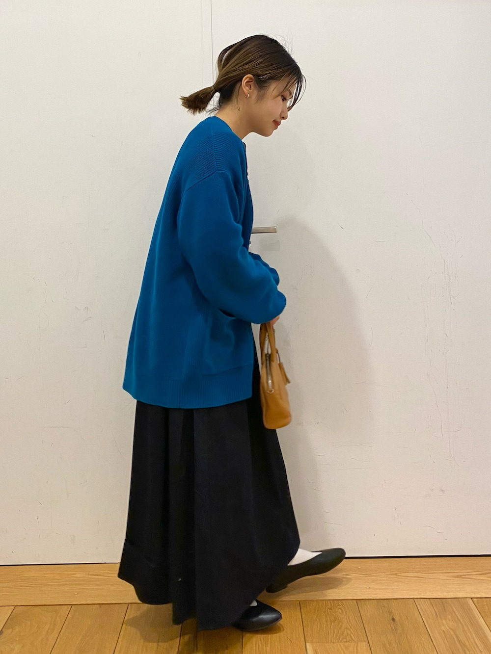 イエロー系のボストンバッグ、ブラック系のパンプス、ブルー系のスカートを着用したレディースの春コーディネートの2枚目の写真