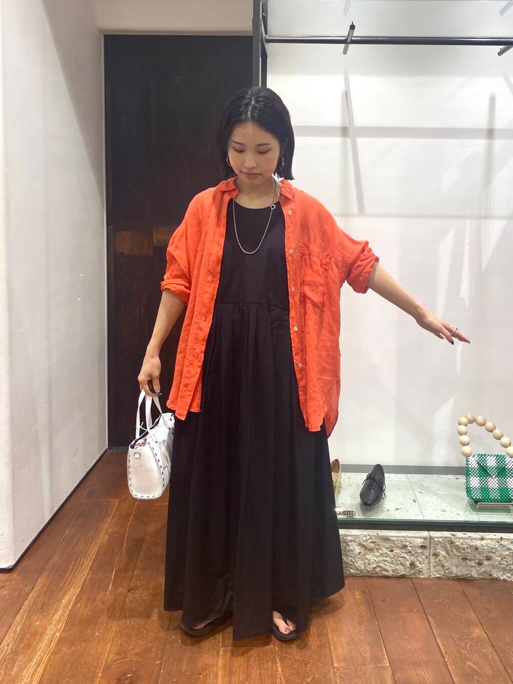 ホワイト系のショルダーバッグ、オレンジ系のTシャツ/カットソー、ブラック系のワンピースを着用したレディースの夏コーディネートの3枚目の写真