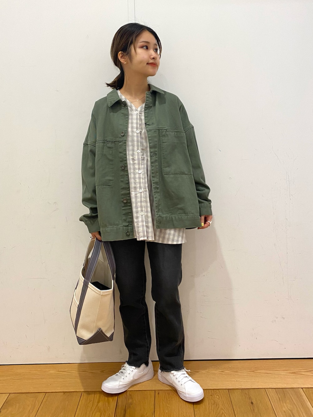 グリーン系のカバーオール、ブラック系のデニムパンツ、ホワイト系のスニーカーを着用したレディースの春コーディネートの2枚目の写真