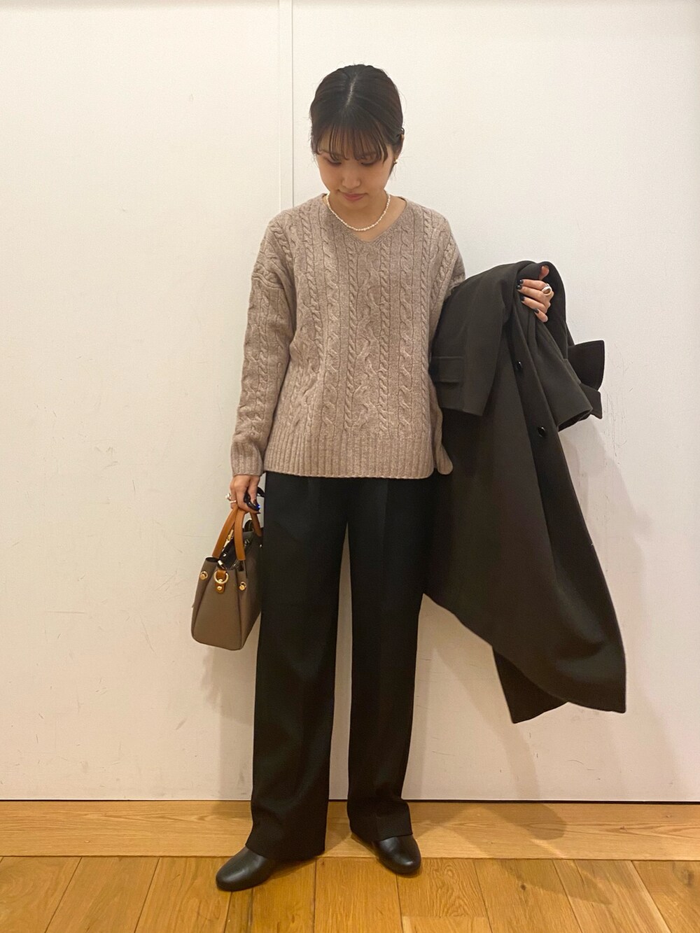 ベージュ系のトートバッグ、グリーン系のステンカラーコート、ブラウン系のニット/セーターを着用したレディースの冬コーディネートの2枚目の写真