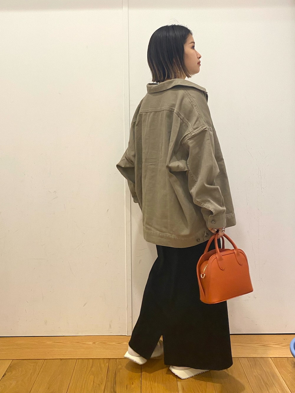 ベージュ系のその他アウター、ブラック系のスカート、オレンジ系のショルダーバッグを着用したレディースの秋コーディネートの2枚目の写真