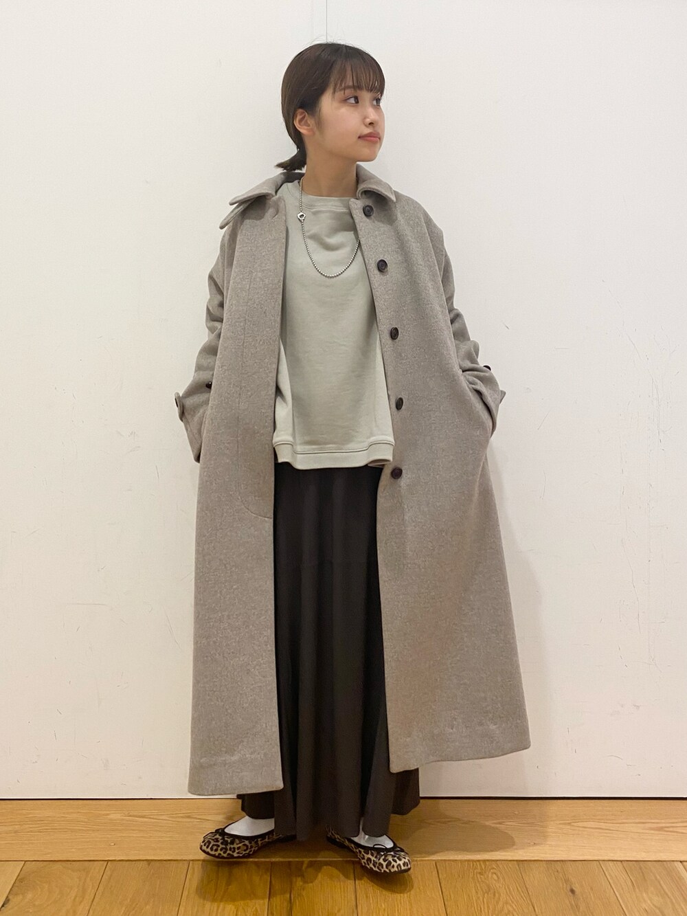 グリーン系のスウェット、グレー系のスカート、グレー系のその他アウターを着用したレディースの冬コーディネートの2枚目の写真