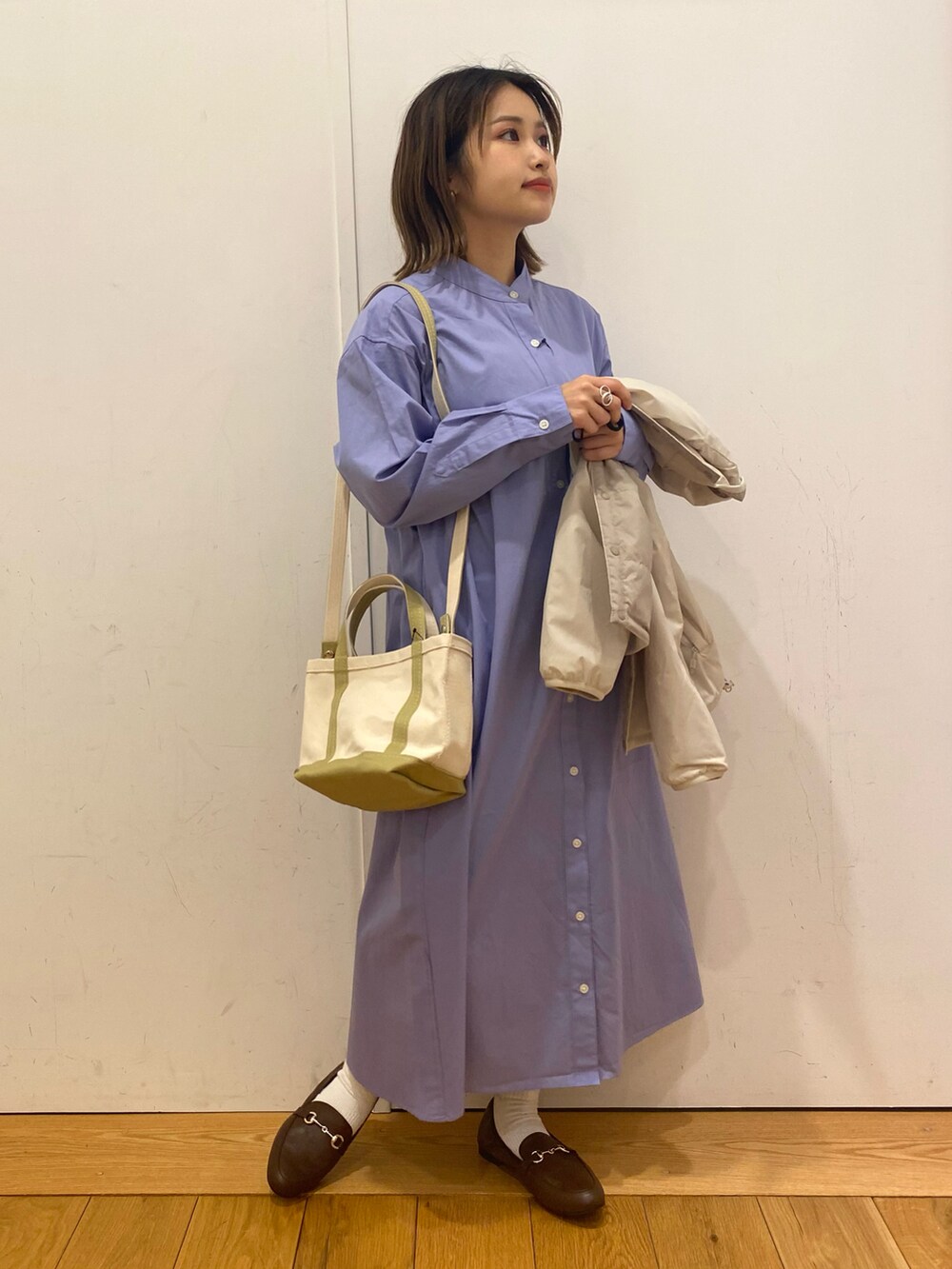 ブルー系のワンピース、グリーン系のハンドバッグ、ブラウン系のローファーを着用したレディースの冬コーディネートの2枚目の写真