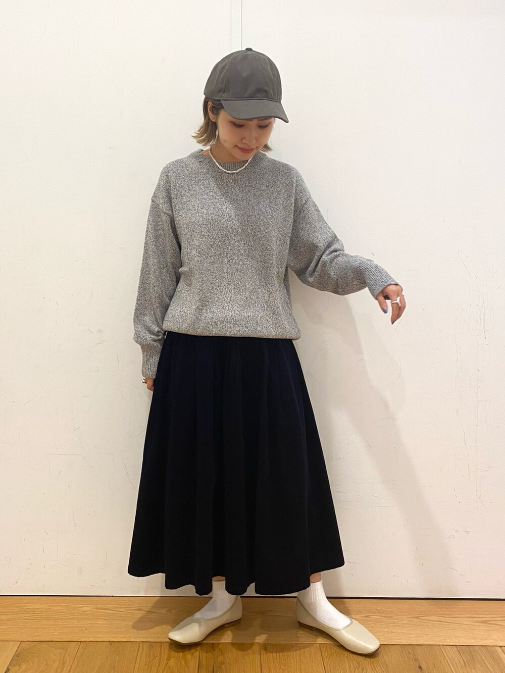 ホワイト系のニット/セーター、ブルー系のスカート、ホワイト系のパンプスを着用したレディースの秋コーディネートの2枚目の写真