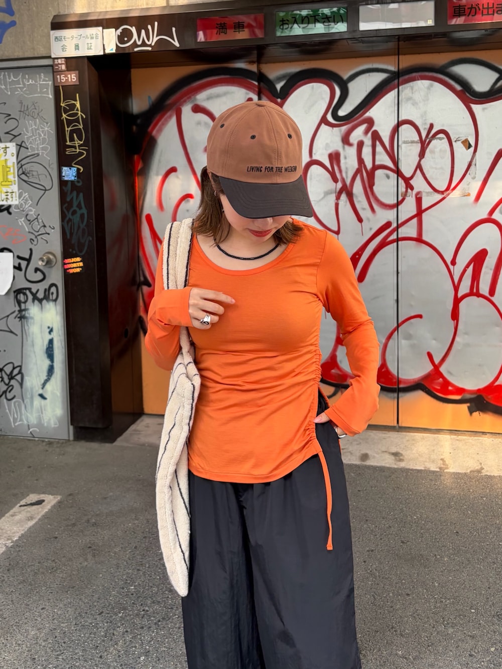 ブラック系のその他パンツ、オレンジ系のTシャツ/カットソー、ホワイト系のトートバッグを着用したレディースの夏コーディネートの3枚目の写真