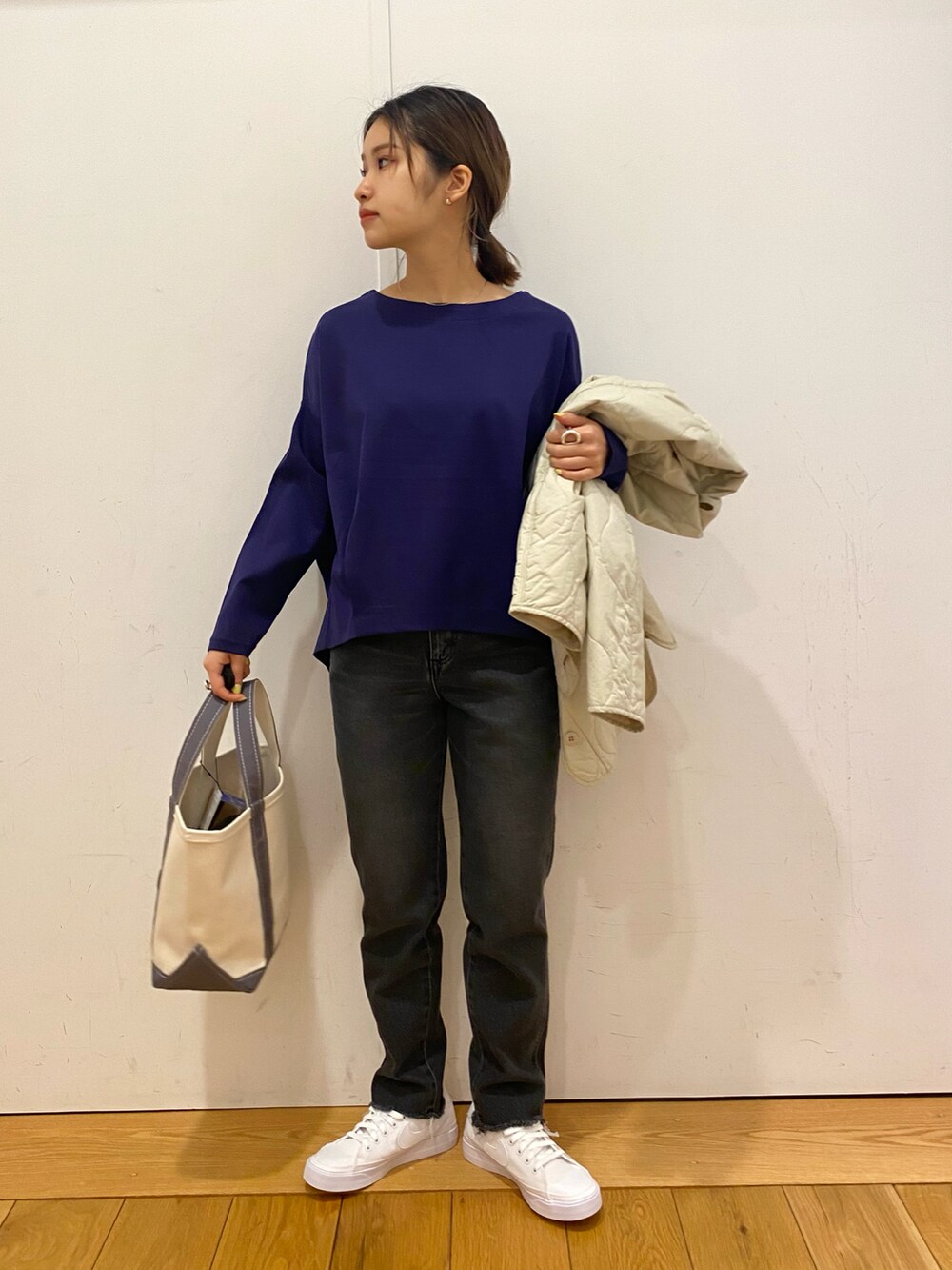 ブラック系のデニムパンツ、ベージュ系のダウンジャケット/コート、ブルー系のTシャツ/カットソーを着用したレディースの春コーディネートの3枚目の写真