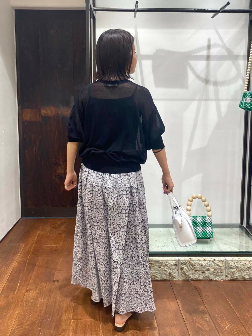 ブラウン系のサンダル、ブルー系のニット/セーター、ホワイト系のショルダーバッグを着用したレディースの夏コーディネートの4枚目の写真