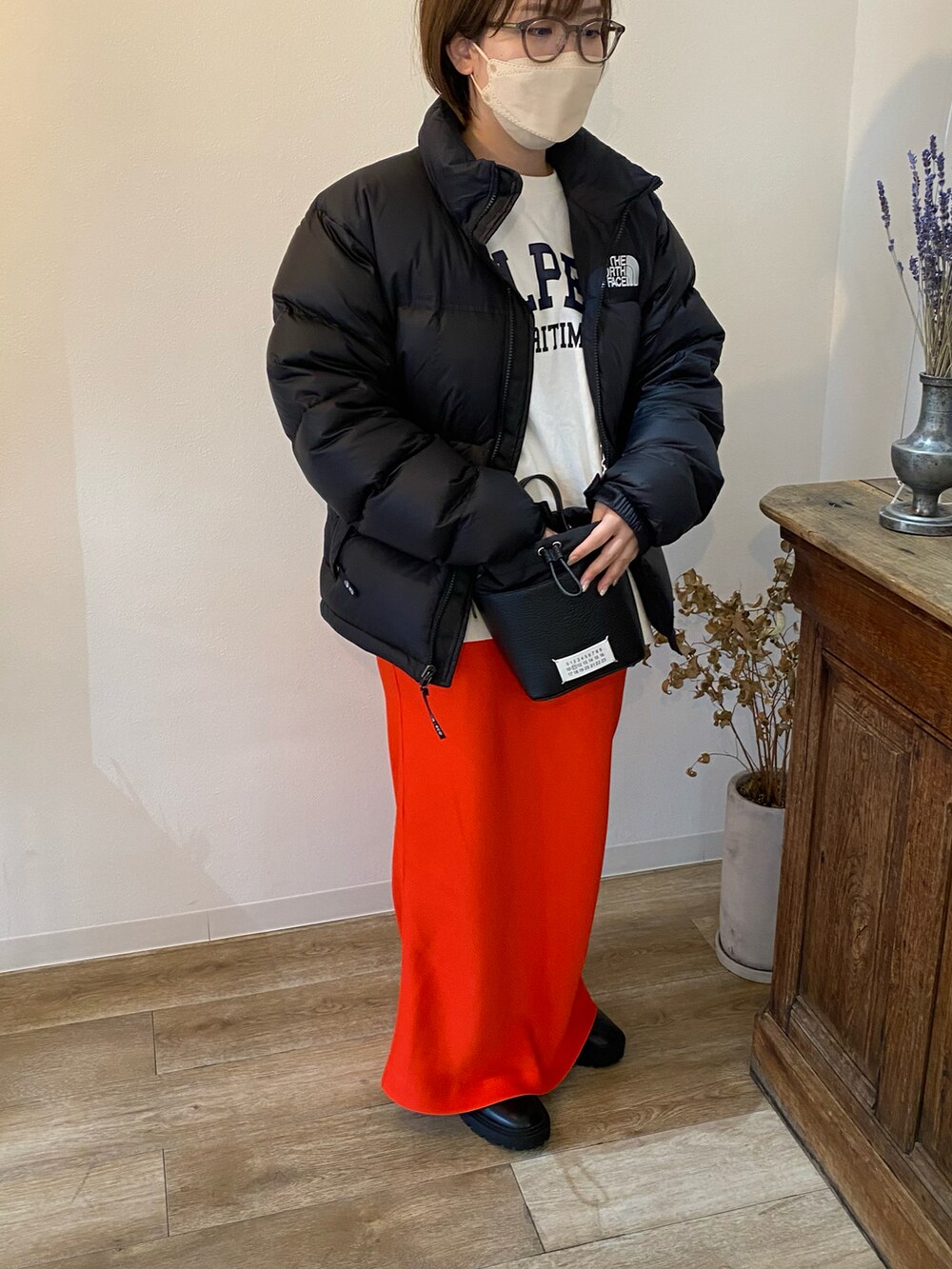 ブラック系のブーツ、レッド系のスカート、ブラック系のショルダーバッグを着用したレディースの春コーディネートの3枚目の写真