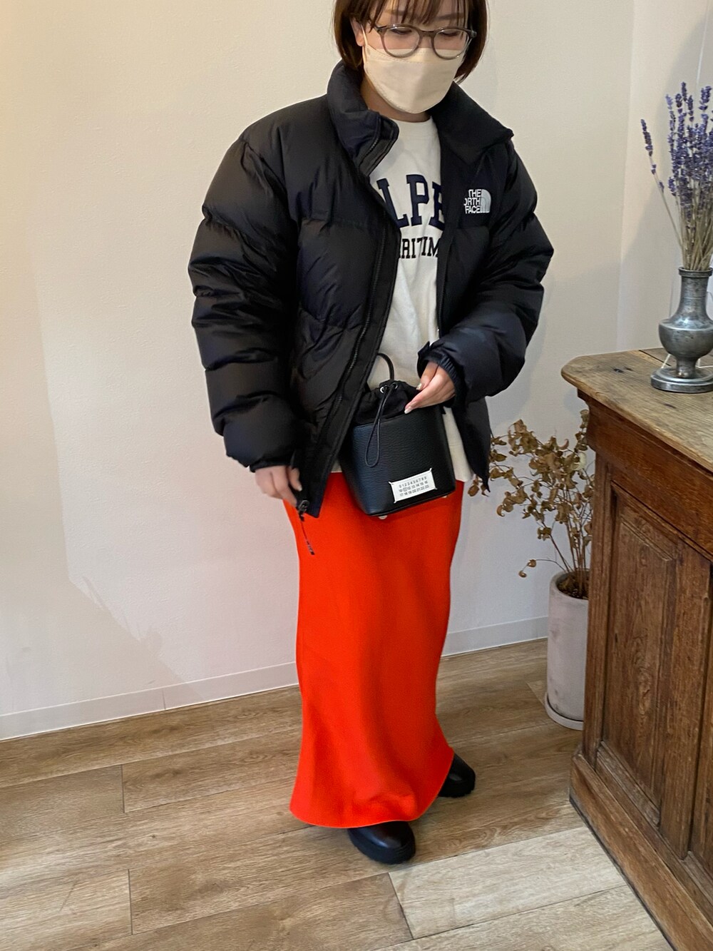 ブラック系のブーツ、レッド系のスカート、ブラック系のショルダーバッグを着用したレディースの春コーディネートの2枚目の写真