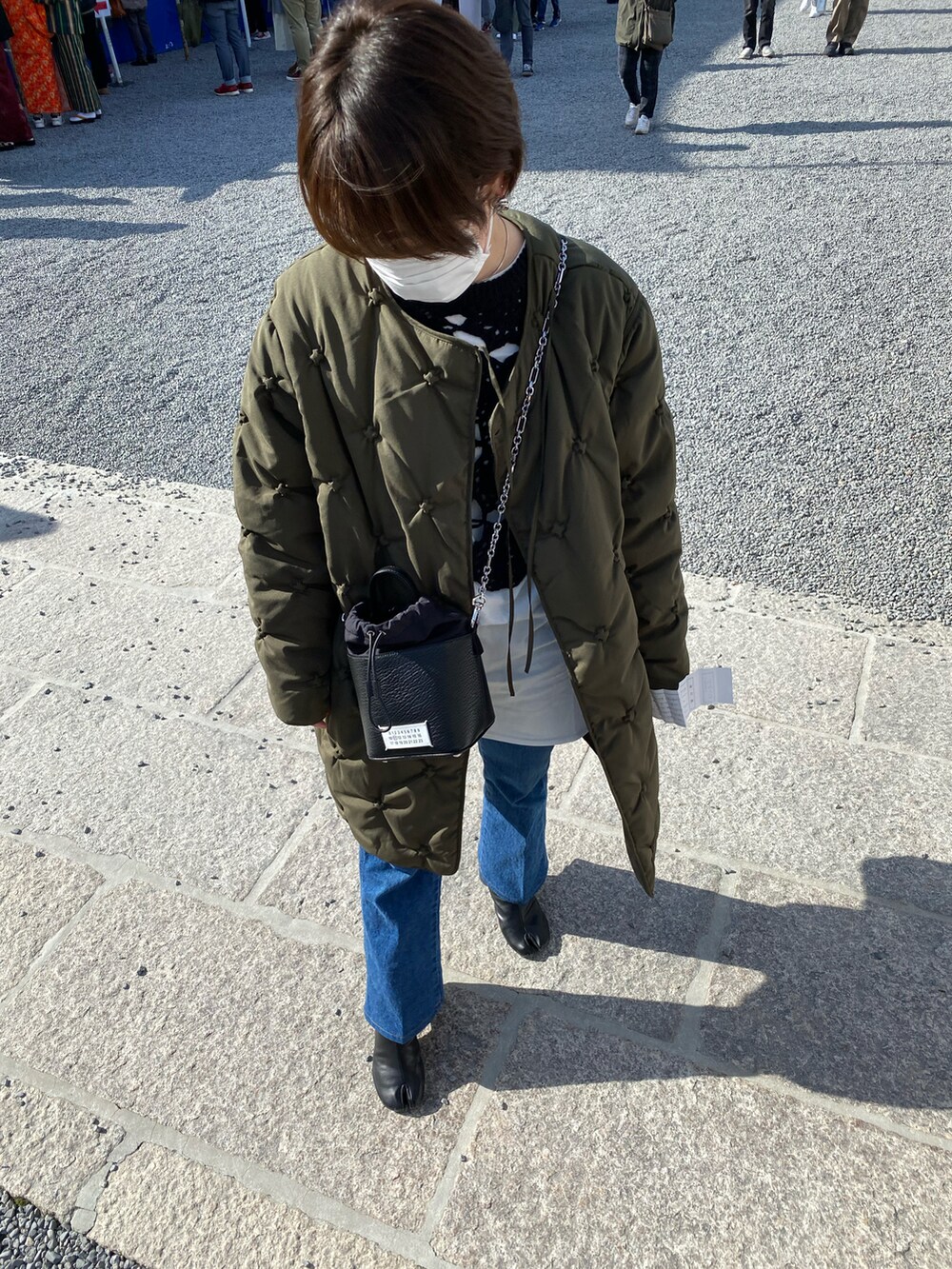 グリーン系のダウンジャケット/コート、ブルー系のデニムパンツ、ブラック系のニット/セーターを着用したレディースの春コーディネートの2枚目の写真